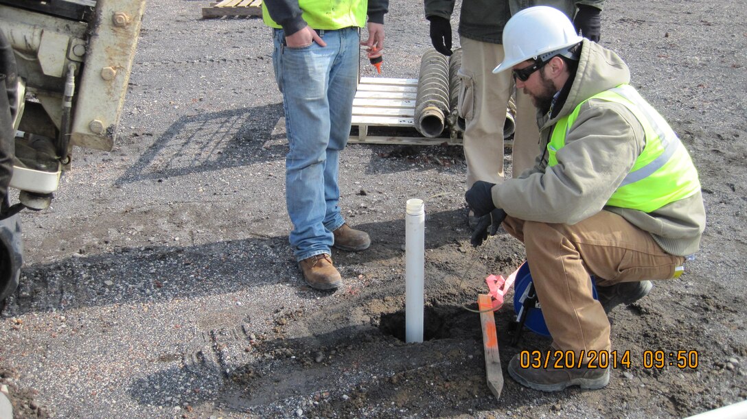Crews examine the initial water level at one of the groundwater monitoring wells at the former Frankford Arsenal. 