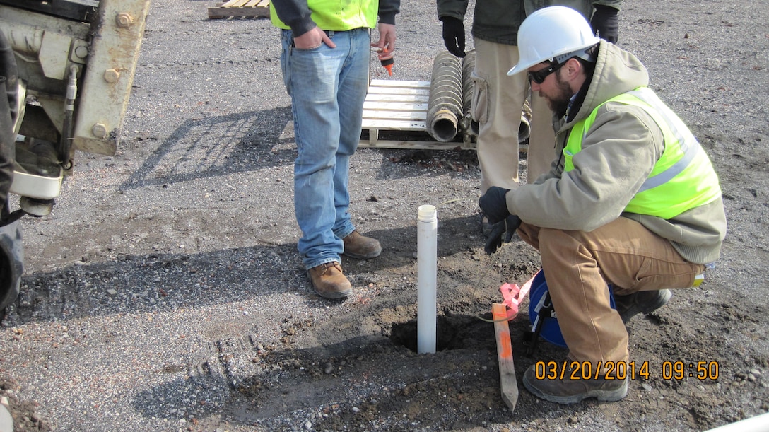 Crews examine the initial water level at one of the groundwater monitoring wells at the former Frankford Arsenal. 