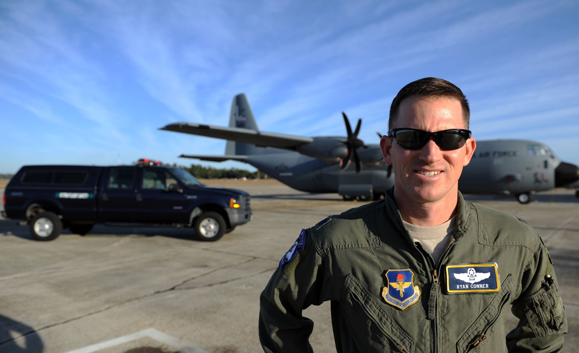 Lt. Col. Ryan Conner, 81st Training Wing safety chief, poses for a photo in front of a C-130J and his unit safety truck on the flight line, Dec. 17, 2014, Keesler Air Force Base, Miss. As the base safety chief and air operations director for Keesler’s 2015 Air Show, Conner is tasked with recruiting acts for the show, handling airspace and ground logistics, and ensuring the air show is a safe event. (U.S. Air Force photo by Airman 1st Class Duncan McElroy)