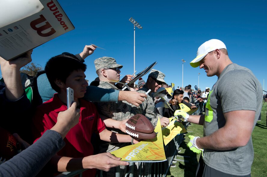 J.J. Watt, Houston Texans defensive end assigned to Pro Bowl Team Carter, autographs footballs and pendants during the Pro Bowl practice at Luke Air Force Base, Arizona, Jan. 22, 2015. The Pro Bowl players were practicing on base to show support for Airmen and to prepare for the game on Sunday. (U.S. Air Force photo by Staff Sgt. Staci Miller)
