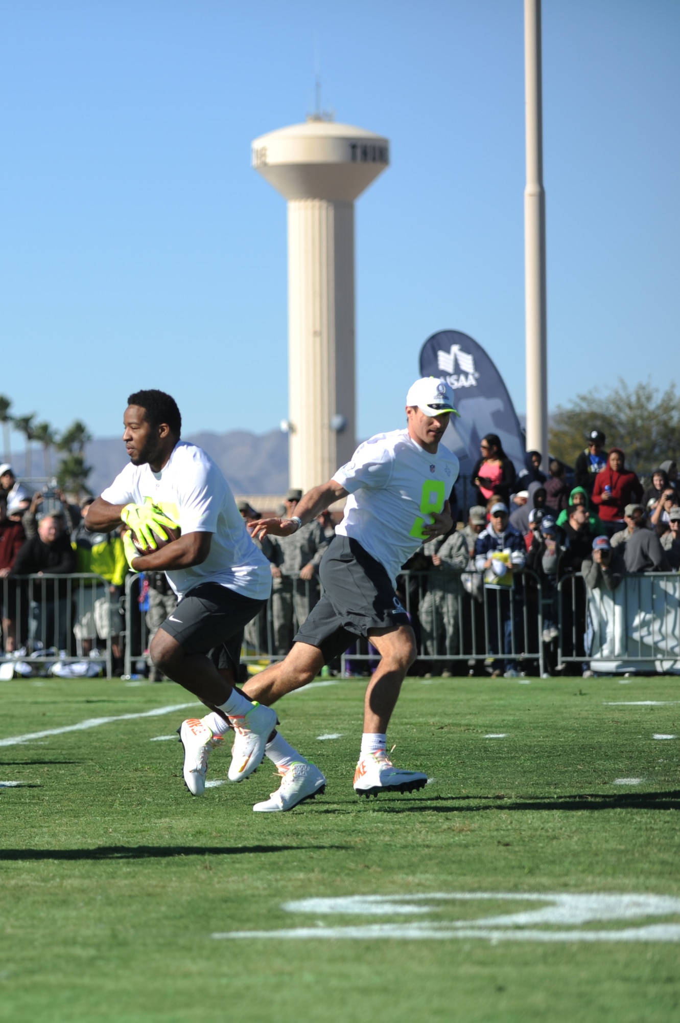 Drew Brees, New Orleans Saints quarterback, hands off the ball to Alfred Morris, Washington Redskins’ running back, both assigned to Pro Bowl Team Carter, at the Pro Bowl practice at Luke Air Force Base, Arizona, Jan. 22, 2015. Players mingled with Airmen and signed autographs after conducting a practice. (U.S. Air Force photo by Staff Sgt. Staci Miller)