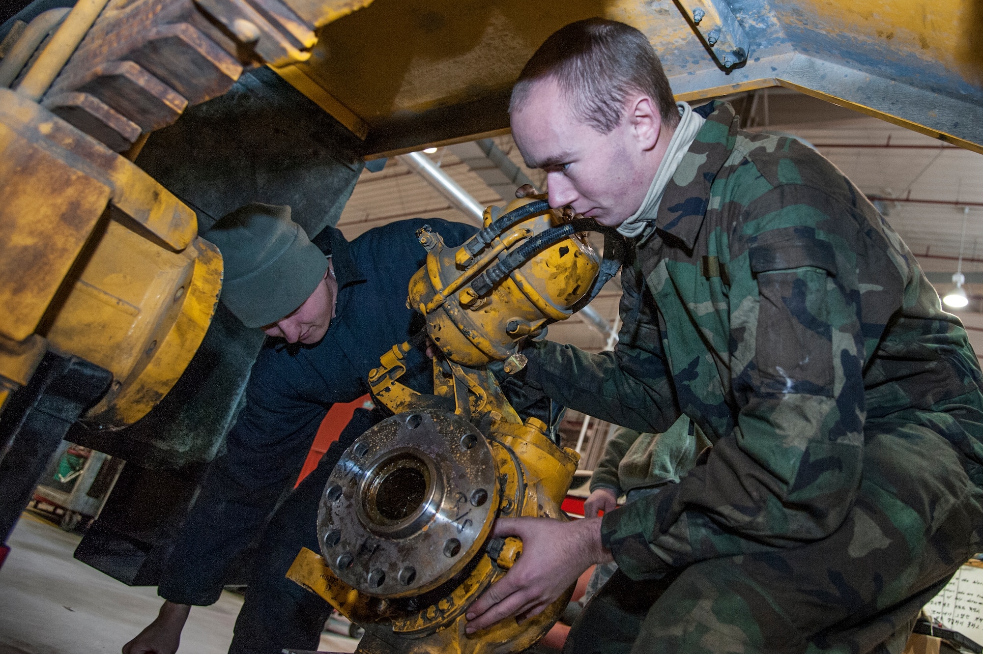 Airman 1st Class Chris O'Connor, 51st Logistics Readiness Squadron special purpose vehicle maintenance apprentance, and Airman 1st Class James Johnson, 51st LRS special purpose vehicle maintenance journeyman, take the hub assembley off a street sweeper at Osan Air Base, Republic of Korea, Dec. 22, 2014. In order to change out a broken inter axel seal, the hub assembley on each side of the street sweeper had to be taken off. (U.S. Air Force photo by Senior Airman Matthew Lancaster)