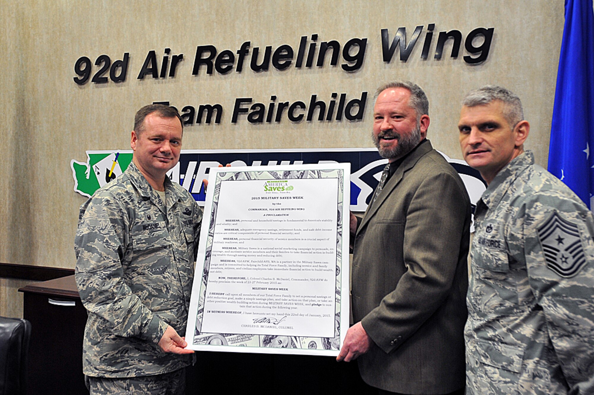 Col. Brian McDaniel, 92nd Air Refueling Wing commander, and Christopher Marble, 92nd Force Support Squadron Airman and Family Readiness Center chief, hold the signed Military Saves Week proclamation alongside Chief Master Sgt. Christian Pugh, 92nd ARW command chief, Feb. 22, 2015, at Fairchild Air Force Base, Wash. Military Saves is an ongoing campaign, but is highlighted this year from Feb. 23 to 28. There are multiple classes and workshops scheduled during the week to educate base members on various financial issues. For more information, visit http://www.militarysaves.org, or call the Airman and Family Readiness Center at 247-2246. (U.S. Air Force photo/Staff Sgt. Veronica Montes)