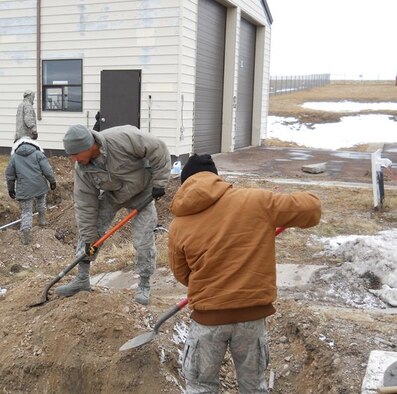 Airmen from the 341st Civil Engineer Squadron work together to replace an underground power line at a Malmstrom Air Force Base missile alert facility Oct. 24.  A short in the line caused the loss of power resulting in 80 feet of underground conduit and 240 feet of cable being replaced. (U.S. Air Force/courtesy photo) 