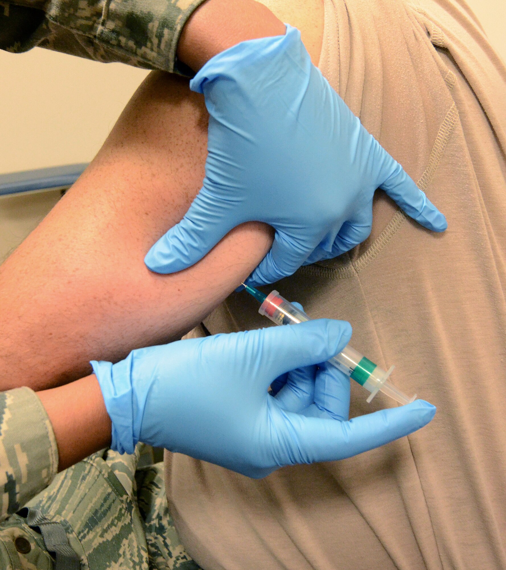 Maj. Sylena Hill "brings the pain" to a deploying 94th Airlift Wing member to ensure they have all required immunizations for their deployment to Southwest Asia; Dobbins Air Reserve Base, Ga., Jan. 2, 2015. (U.S. Air Force photo/Brad Fallin)