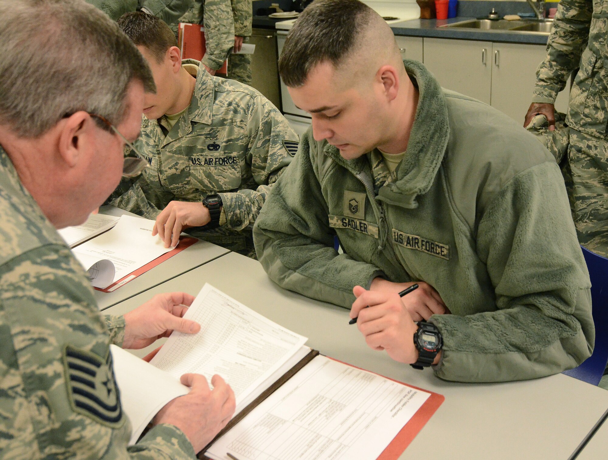 Master Sgt. Jonathon Sadler reviews his mobility folder with Tech. Sgt. Alan McKibben, to ensure all information is correct and up to date for his deployment to Southwest Asia; Dobbins Air Reserve Base, Ga., Jan. 2, 2015. (U.S. Air Force photo/Brad Fallin)