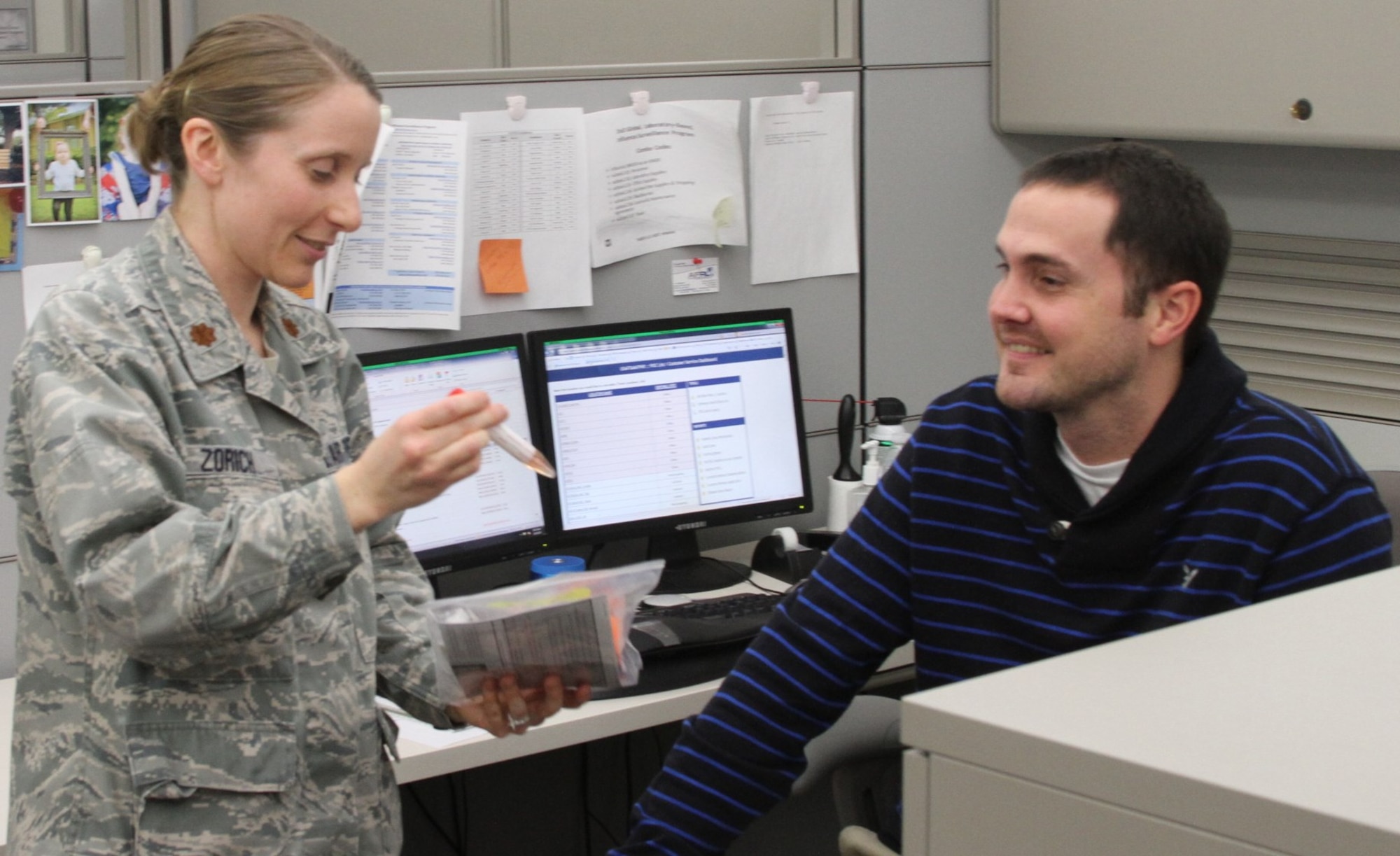 Pictured are Maj Shauna Zorich,  preventative medicine consultant with USAFSAM’s Epidemiology Consult Service, and Josh Cockerham, customer service and supply technician. One of Josh's roles is making sure all of the program's sentinel sites are supplied with respiratory viral specimen collection kits. Maj Zorich holds a collection kit and a tube of viral transport media (VTM), which holds specimens that come to USAFSAM for analysis (Contributed photo)