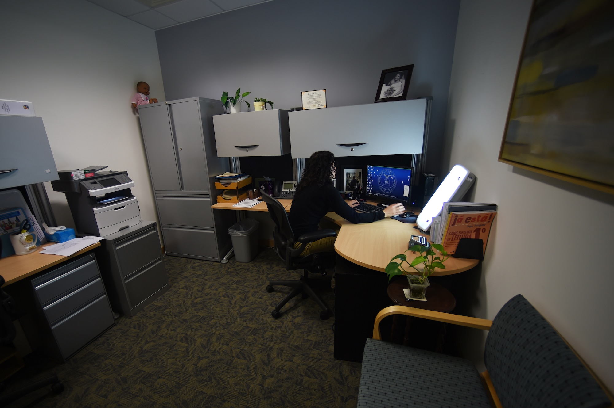 Kristina Da Silva E Silva, 423rd Medical Squadron occupational therapist, glances at her seasonal affective disorder lamp while she works at her office on RAF Alconbury, England, Jan. 16, 2015. Typically, people who use SAD lamps should sit two to three feet from the light and look into it for 30 to 45 minutes per day. (U.S. Air Force photo by Staff Sgt. Jarad A. Denton/Released)