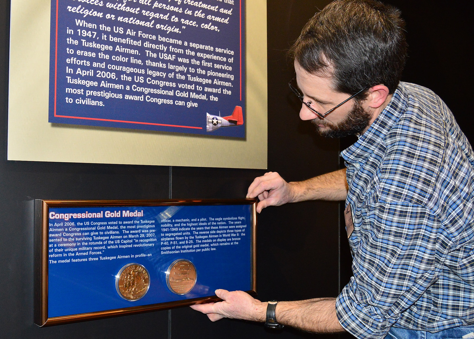 DAYTON, Ohio -- The Tuskegee Airmen Congressional Gold Medal being installed by Exhibits Specialist Caleb Still in the WWII Gallery at the National Museum of the U.S. Air Force. In April 2006, the U.S. Congress voted to award the Tuskegee Airmen a Congressional Gold Medal, the most prestigious award Congress can give to civilians. (U.S. Air Force photo) 
