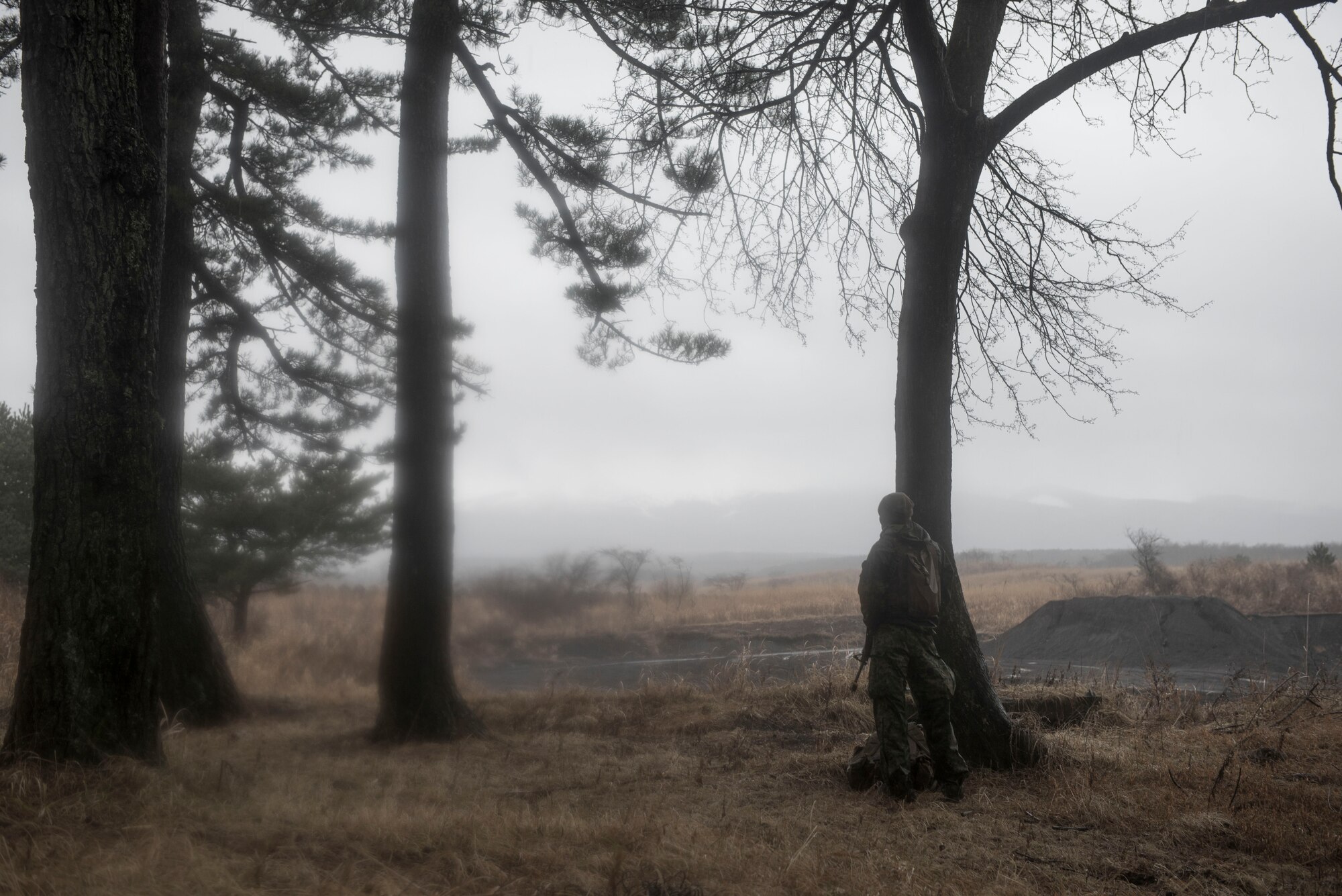 A Marine with the 1st Batallion, 1st Marines, watches a field for movement while searching for aircrew at Camp Fuji, Japan, Jan. 16, 2015. Marines and Sailors acted as enemy aggressors, practicing their patrolling techniques, while searching for Air Force aircrew, who were simultaneously training their survival, evasion, resistance and escape techniques. (U.S. Air Force photo by Staff Sgt. Cody H. Ramirez/Released)