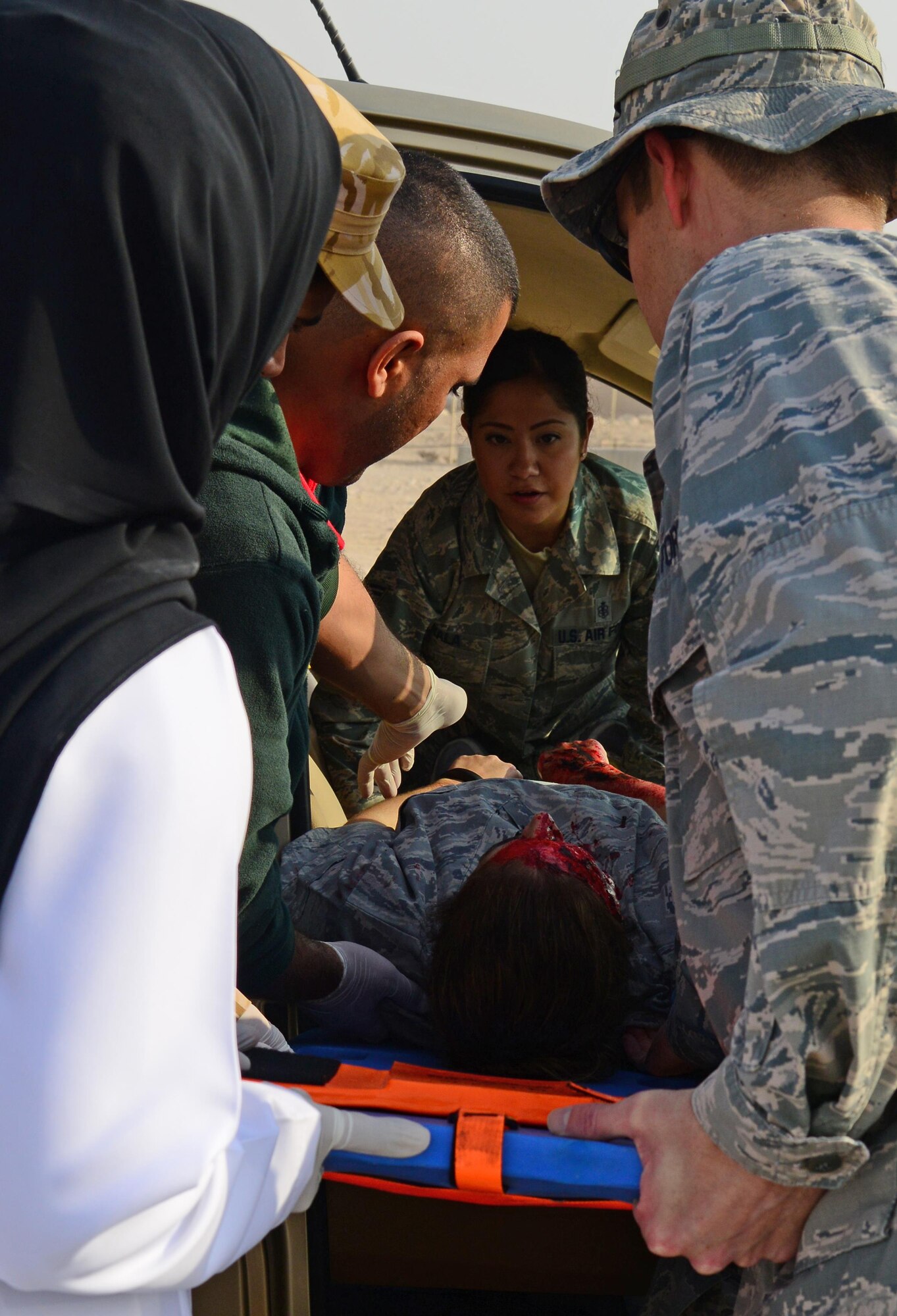 U.S. Air Force and Qatari medical personnel move the simulated victim of a motor vehicle accident onto a stretcher during a joint training event, Jan. 18, 2015, at Al Udeid Air Base, Qatar. The training required 379th Expeditionary Medical Group Airmen and Qatari medics to integrate and exchange knowledge that will help them jointly respond to real-world medical emergencies at Al Udeid. (U.S. Air Force photo by Senior Airman Kia Atkins)