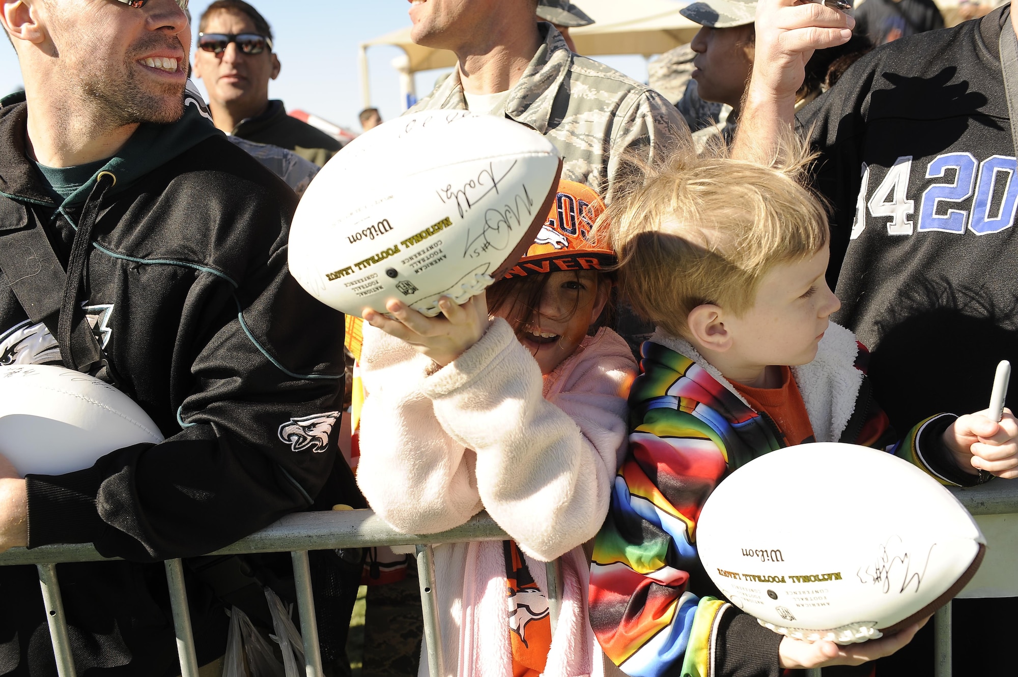 Fans hold up autographed footballs at the Pro Bowl practice at Luke Air Force Base, Arizona, Jan. 22, 2015. The Pro Bowl players came out to Luke to show support for the Airmen and their families. The players took photos with the Airmen and did autographs for them as well. (U.S. Air Force photo by Staff Sgt. Staci Miller)