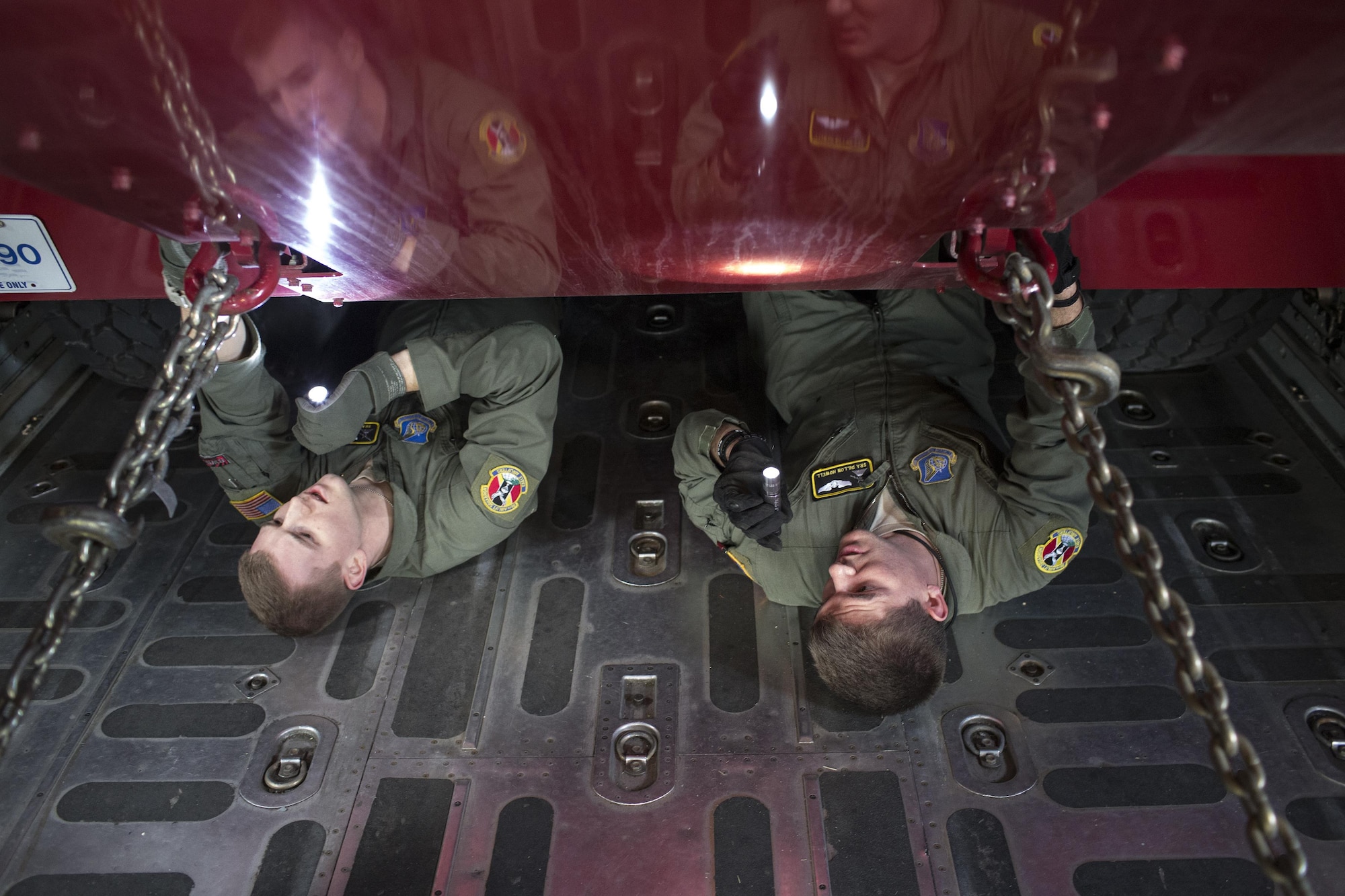 Senior Airmen Christopher Hofer and Dillon Howell inspect chains that secure a P-19 Aircraft Rescue Firefighting Vehicle inside of a C-130 Hercules Jan. 14, 2015, at Yokota Air Base, Japan, during a readiness inspection. The inspection was designed to evaluate areas such a rapid mobility response to simulated contingencies. The Airmen are both 36th Airlift Squadron loadmasters. (U.S. Air Force photo/Osakabe Yasuo)