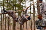 A Tarheel Challenge Academy cadet pulls himself across a rope at the obstacle course while fellow cadets encourage him to finish, at Camp Butner, N.C., on Jan. 21, 2015, as part of a two-day event supported by the North Carolina National Guard. Cadets also navigated a land navigation course and a 5K road-march as part of the 22-week long program whose goal is to intervene in the lives of 16-18 year old high school dropouts and instill in them the traits and skills they need to become productive citizens.  
