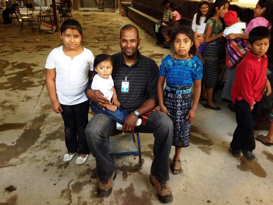 Senior Master Sgt. Larry Gallo, 433rd Logistics Readiness Squadron, maintenance support section chief from Joint Base San Antonio-Lackland, Texas poses with children in a village near San Raimundo, Guatemala. His job that day was to entertain the children with coloring while their parents are being seen by the medical staff. Gallo has been volunteering with T.I.M.E. for Christ Medical Ministries for seven years. 