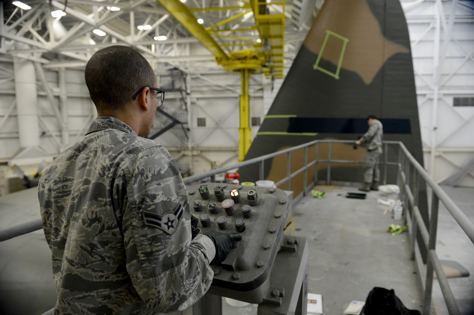 Airman 1st Class Julian Engelhardt, 62nd Maintenance Squadron structural maintenance technician, operates a lift while Senior Airman Justin Lounder, 62nd MXS aircraft structural maintenance technician, guides him Jan. 13, 2015, during the repainting of a C-130 Hercules at Joint Base Lewis-McChord, Wash. Airmen from the 62nd MXS spent more than two months repainting the C-130 in Vietnam era camouflage scheme.  The aircraft was painted for the McChord Air Museum. (U.S. Air Force photo/Airman 1st Class Keoni Chavarria)