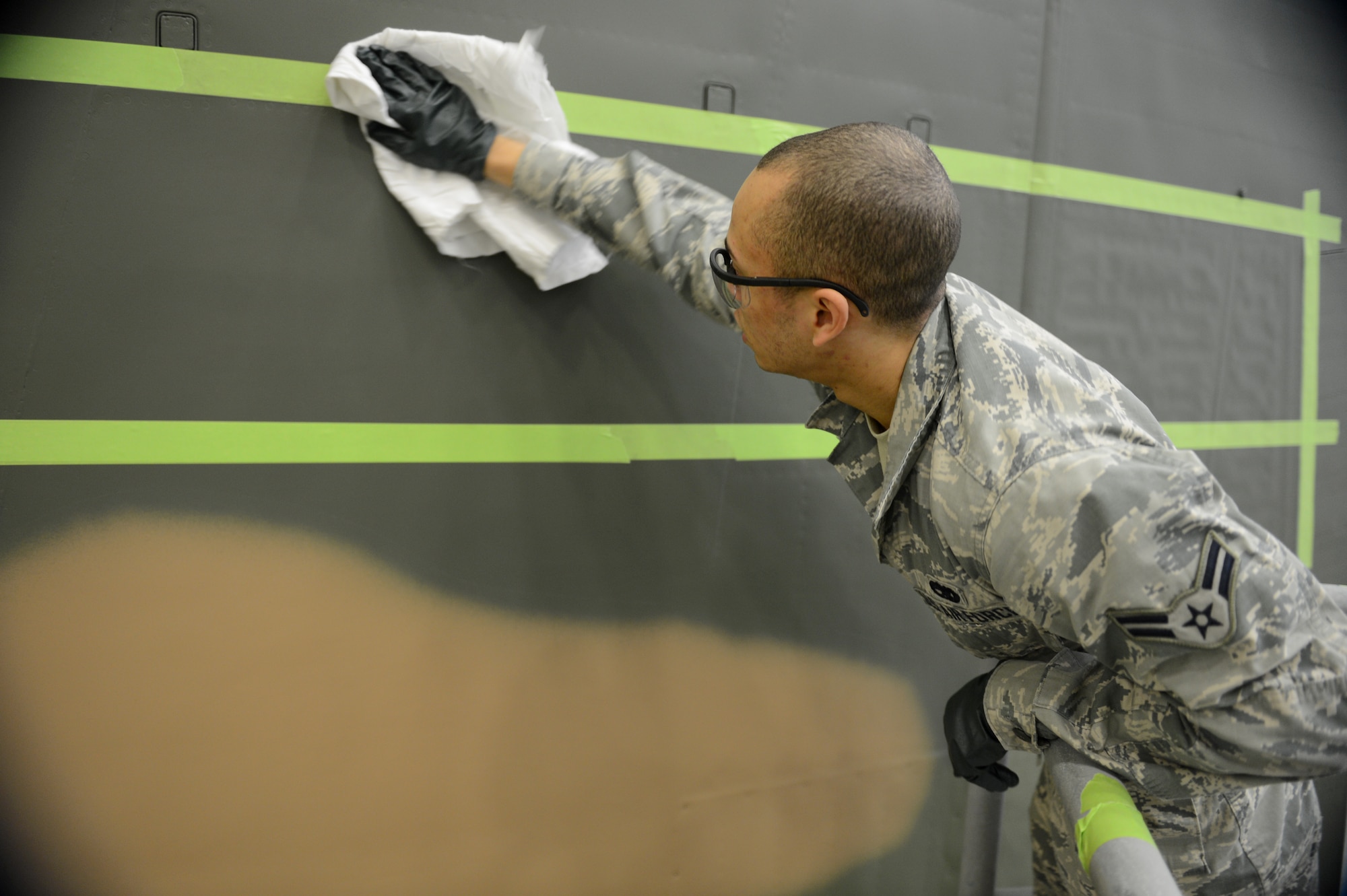 Airman 1st Class Julian Engelhardt, 62nd Maintenance Squadron structural maintenance technician, wipes dust off of a C-130 Hercules Jan. 13, 2015, during the repainting of the aircraft at Joint Base Lewis-McChord, Wash. Airmen from the 62nd MXS spent more than two months repainting the C-130 in Vietnam era camouflage scheme.  The aircraft was painted for the McChord Air Museum. (U.S. Air Force photo/Airman 1st Class Keoni Chavarria)