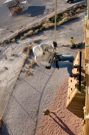An Army Junior Reserve Officer Training Corps cadet descends down the side of a rappelling wall while a member of the 58th Rescue Squadron holds the rope below at Nellis Air Force Base, Nev., Jan. 23, 2015. Approximately 102 cadets from three local Army JROTC units participated in the rappelling with members of the 58th RQS. (U.S. Air Force photo by Airman 1st Class Mikaley Towle)    