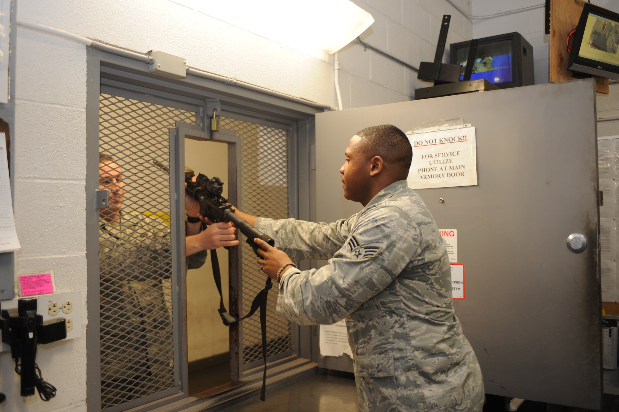 U.S. Air Force Senior Airman Deiron Armstead, 355th Security Forces Squadron arms room attendant, issues Staff Sgt. Tyler Rivas, 355th SFS NCO in charge of armory operations, a weapon at the armory at Davis-Monthan Air Force Base, Ariz., Jan. 20, 2015. Defenders who work flight line security, entry control, and patrol are issued weapons every day before their shift and return the weapons upon completion of their shift. (U.S. Air Force photo by Airman 1st Class Cheyenne Morigeau/Released)