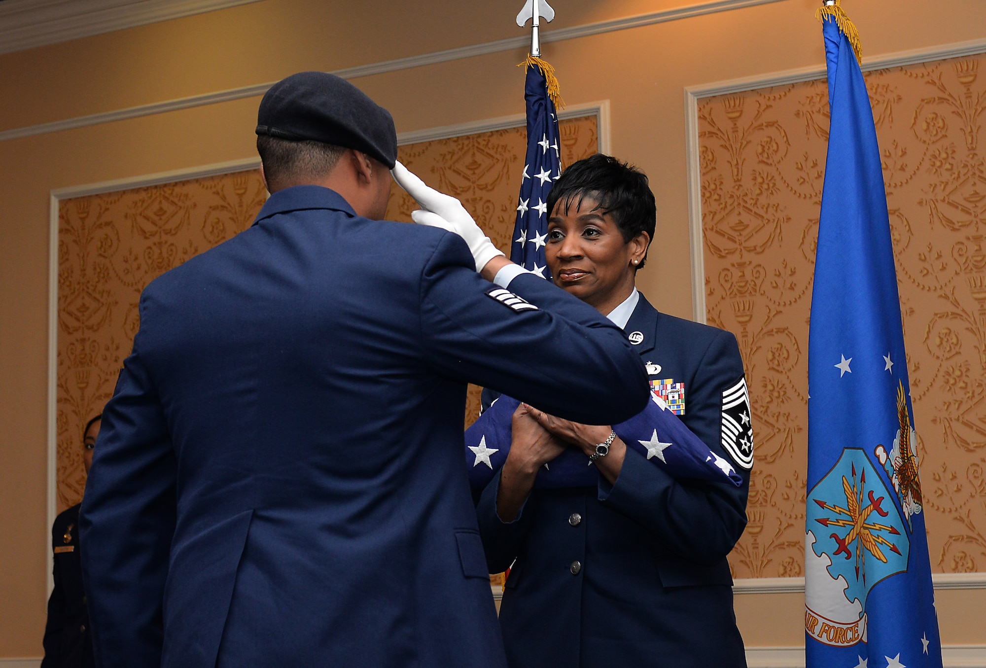U.S. Air Force Staff Sgt. Maurice Carter, Navy Consolidated Brig USAF liaison, presents the American flag to Chief Master Sgt. Trae King, 633rd Air Base Wing command chief, during her retirement ceremony at Langley Air Force Base, Va., Jan. 23, 2015. King was honored for her 30 years of service, and was the senior-enlisted leader responsible for advising wing commanders on enlisted issues and provided senior-enlisted mentorship to more than 6,000 Air Force and U.S. Army personnel. (U.S. Air Force photo by Staff Sgt. Antoinette Gibson/Released)