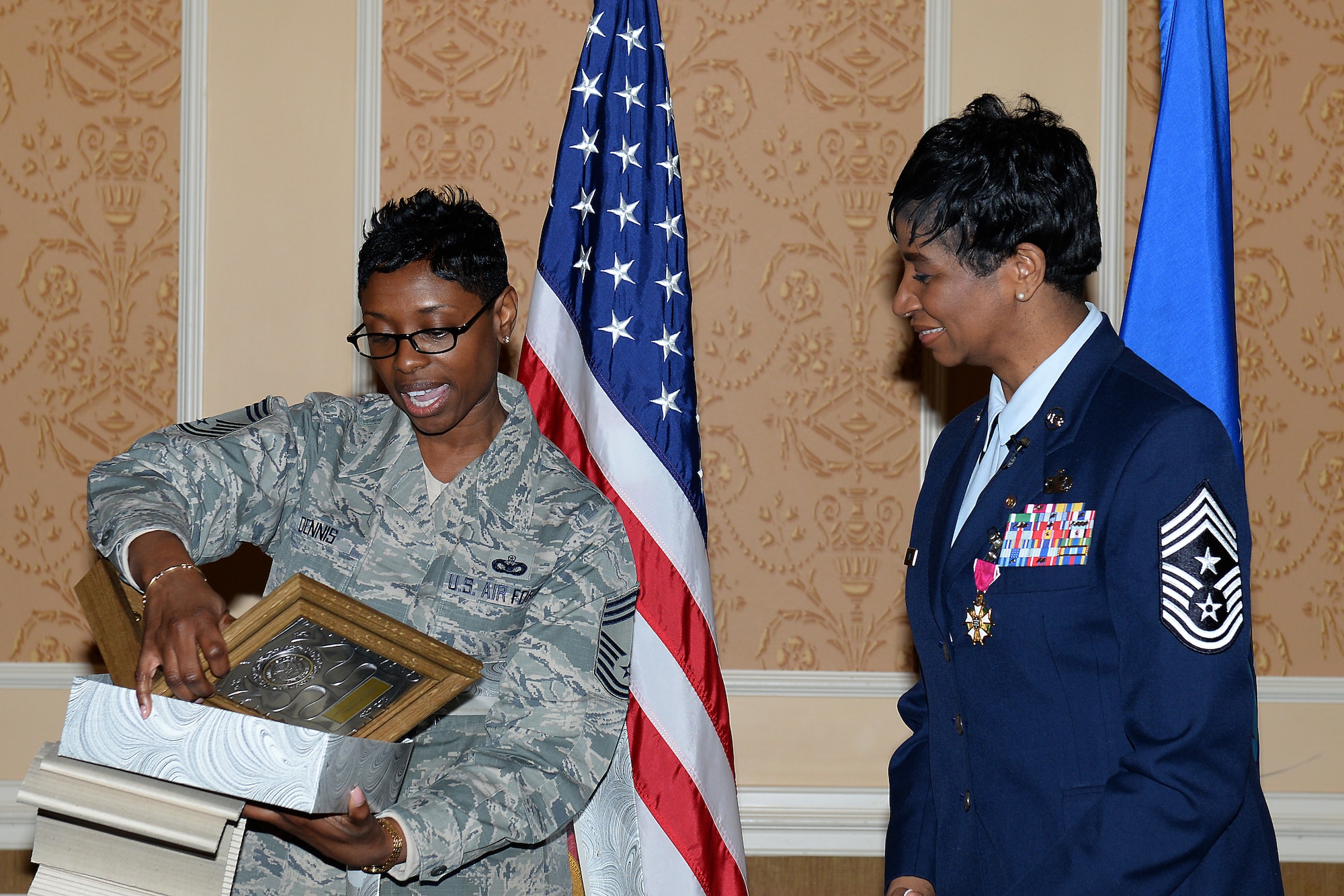 U.S. Air Force Chief Master Sgt. Tamara Dennis, United States Air Force Europe Forces, 86th Security Forces Squadron superintendent, presents Chief Master Sgt. Trae King, 633rd Air Base Wing command chief, with a memento at King’s retirement ceremony at Langley Air Force Base, Va., Jan. 23, 2015.  King, who was born and raised in Cleveland, Ohio, joined the Air Force in April 1985. (U.S. Air Force photo by Staff Sgt. Antoinette Gibson/Released)