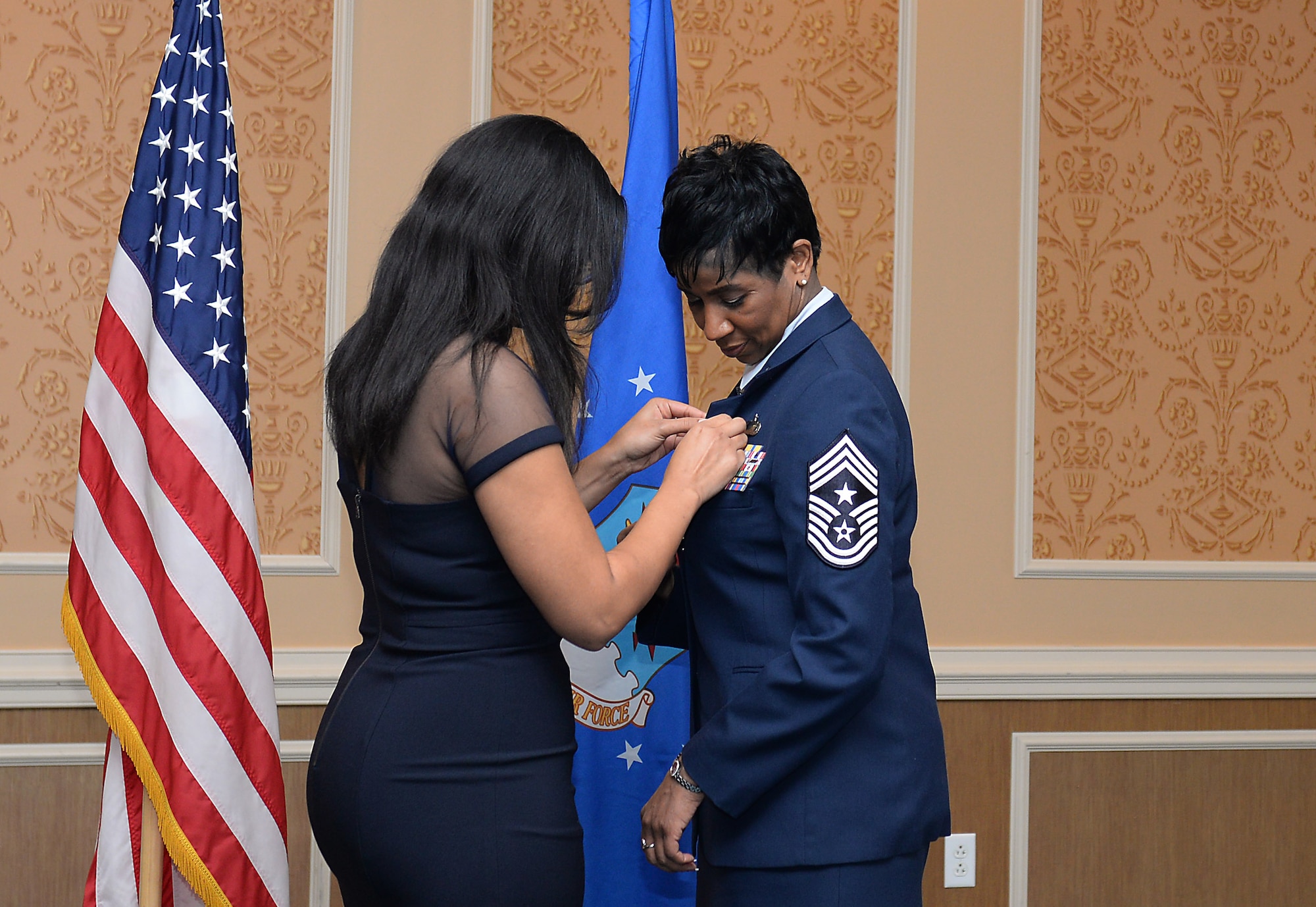 Tashawna Tolbert, daughter of Chief Master Sgt. Trae King, the 633rd Air Base Wing command chief, places a retirement pin on her mother during King’s retirement ceremony at Langley Air Force Base, Va., Jan. 23, 2015. Before assuming the position as command chief at Langley, King was the Senior Enlisted Leader at Joint Base-Anacostia Bolling, D.C. (U.S. Air Force photo by Staff Sgt. Antoinette Gibson/Released)