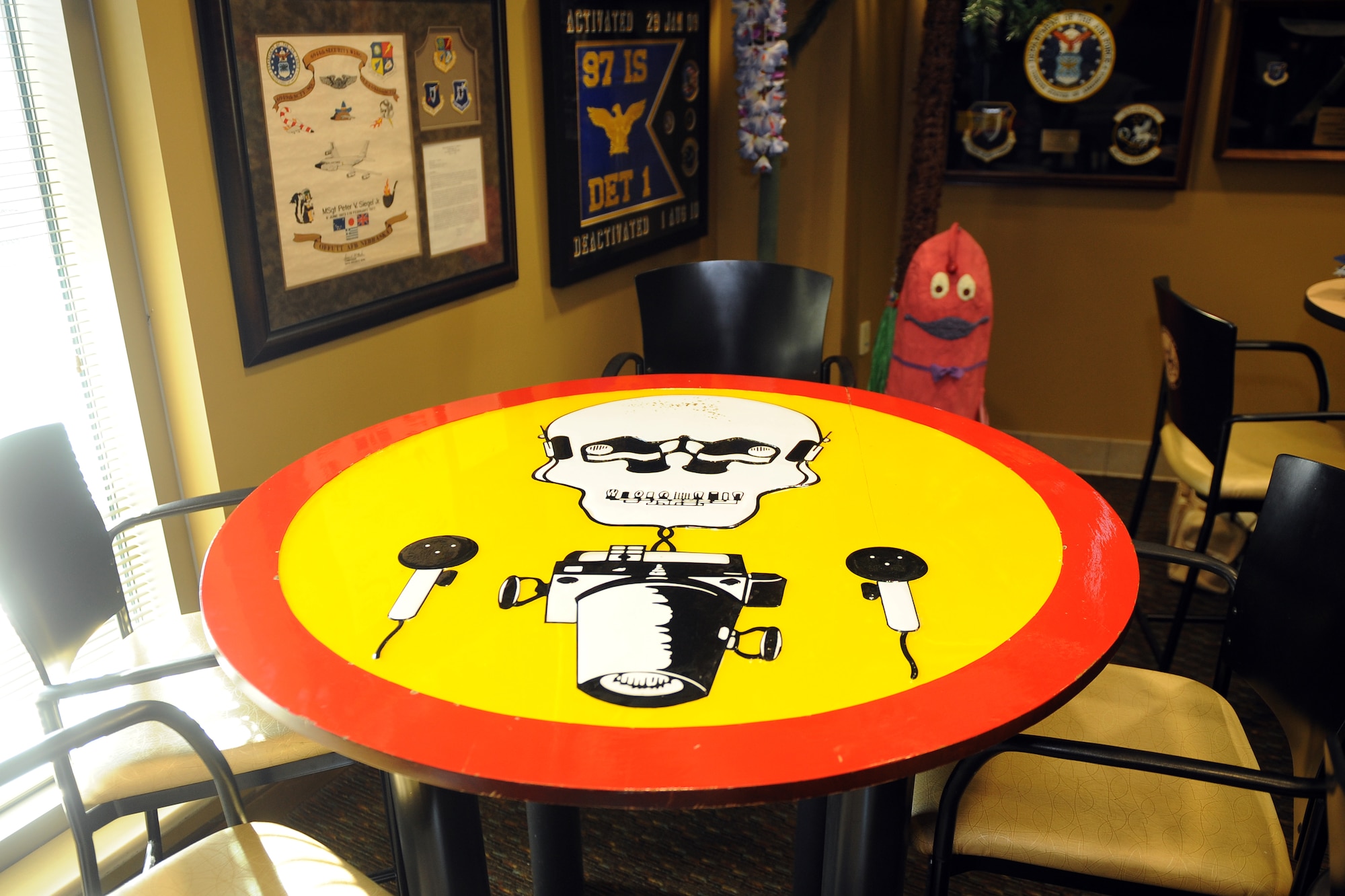 A café table with the 97th Intelligence Squadron shield sits inside the heritage room Jan. 16, Offutt Air Force Base, Neb.  Heritage items adorn the room making for a space uniquely 97th IS.  (U.S. Air Force photo by Josh Plueger/Released)