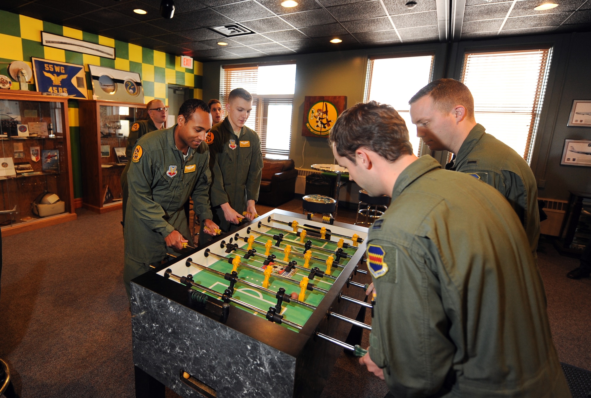 Airmen assigned to the 45th Reconnaissance Squadron play a couple of games of foosball inside their heritage room on Jan. 14, Offutt Air Force Base, Neb.  The walls geometric paint scheme is based on their unit’s scarves from both the past and present.   (U.S. Air Force photo by Josh Plueger/Released)