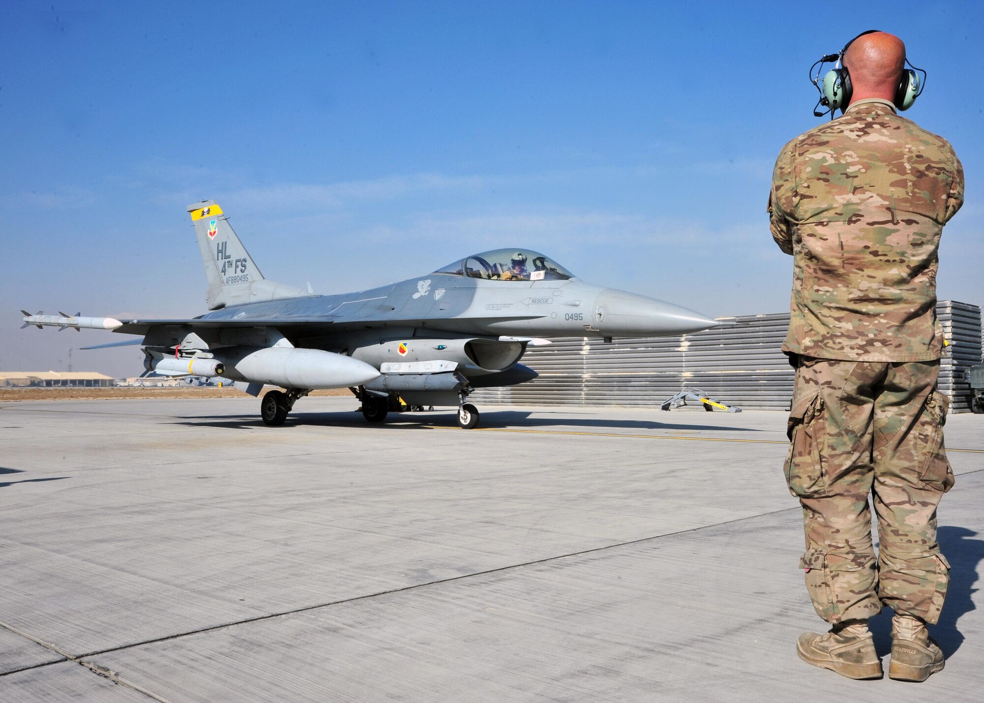 U.S. Air Force Senior Airman Brandon Shinkle, 455th Expeditionary Aircraft Maintenance Squadron crew chief, uses arm signals to communicate with U.S. Air Force Capt. Shayne Carroll, 4th Expeditionary Fighter Squadron F-16 pilot, prior to marshalling the F-16 Fighting Falcon onto a taxiway Jan. 9, 2015 at Bagram Airfield, Afghanistan. The F-16 is a multi-role fighter aircraft that provides air superiority enabling freedom of movement for troops on the ground as well as close air support for troops engaged in combat. It provides a relatively low-cost, high-performance weapon system for the United States and allied nations. (U.S. Air Force photo by Staff Sgt. Whitney Amstutz)