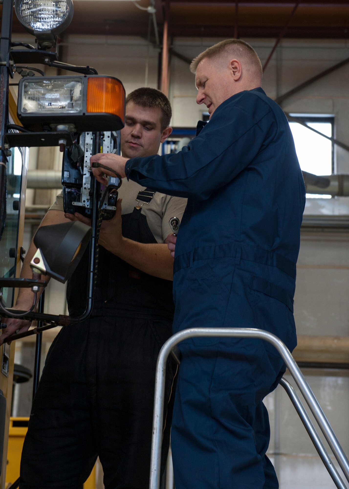 Col. Michael Grismer, 436th Airlift Wing commander, and Staff Sgt. Erik Struss, 436th Logistics Readiness Squadron vehicle maintenance, replace a side-view mirror on an Oshkosh snow plow Jan. 22, 2015, in the heavy vehicle maintenance shop on Dover Air Force Base, Del. The heavy vehicle maintenance shop is responsible for maintaining Team Dover’s large vehicles. (U.S. Air Force photo/Airman 1st Class Zachary Cacicia)