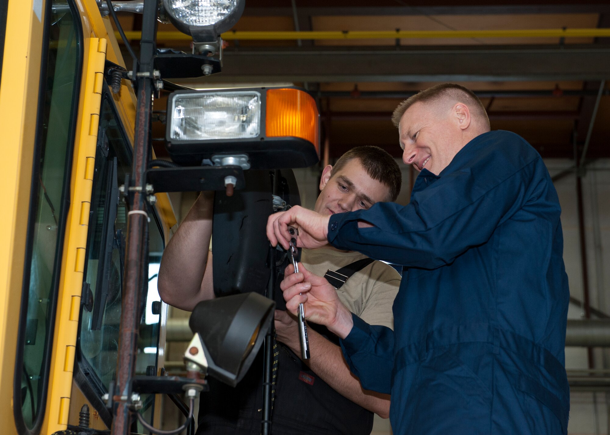Col. Michael Grismer, 436th Airlift Wing commander, and Staff Sgt. Erik Struss, 436th Logistics Readiness Squadron vehicle maintenance, replace a side-view mirror on an Oshkosh snow plow Jan. 22, 2015, in the heavy vehicle maintenance shop on Dover Air Force Base, Del. Grismer took time out of his day to do some hands-on work with Team Dover Airmen. (U.S. Air Force photo/Airman 1st Class Zachary Cacicia)