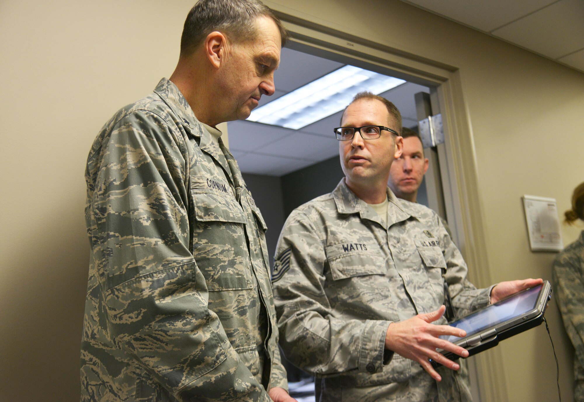 Tech. Sgt. Brian Watts, 92nd Aerospace Medicine Squadron force health management NCO in charge, demonstrates his equipment for Brig. Gen. (Dr.) Kory Cornum, Air Mobility Command command surgeon, during a tour of the clinic, Jan. 13, 2015, at Fairchild Air Force Base, Wash. The tour included stops at the physical therapy, public health, flight medicine and family health. Cornum also presented the Air Mobility Command awards  during an all-call. (U.S. Air Force photo/Senior Airman Janelle Patiño)