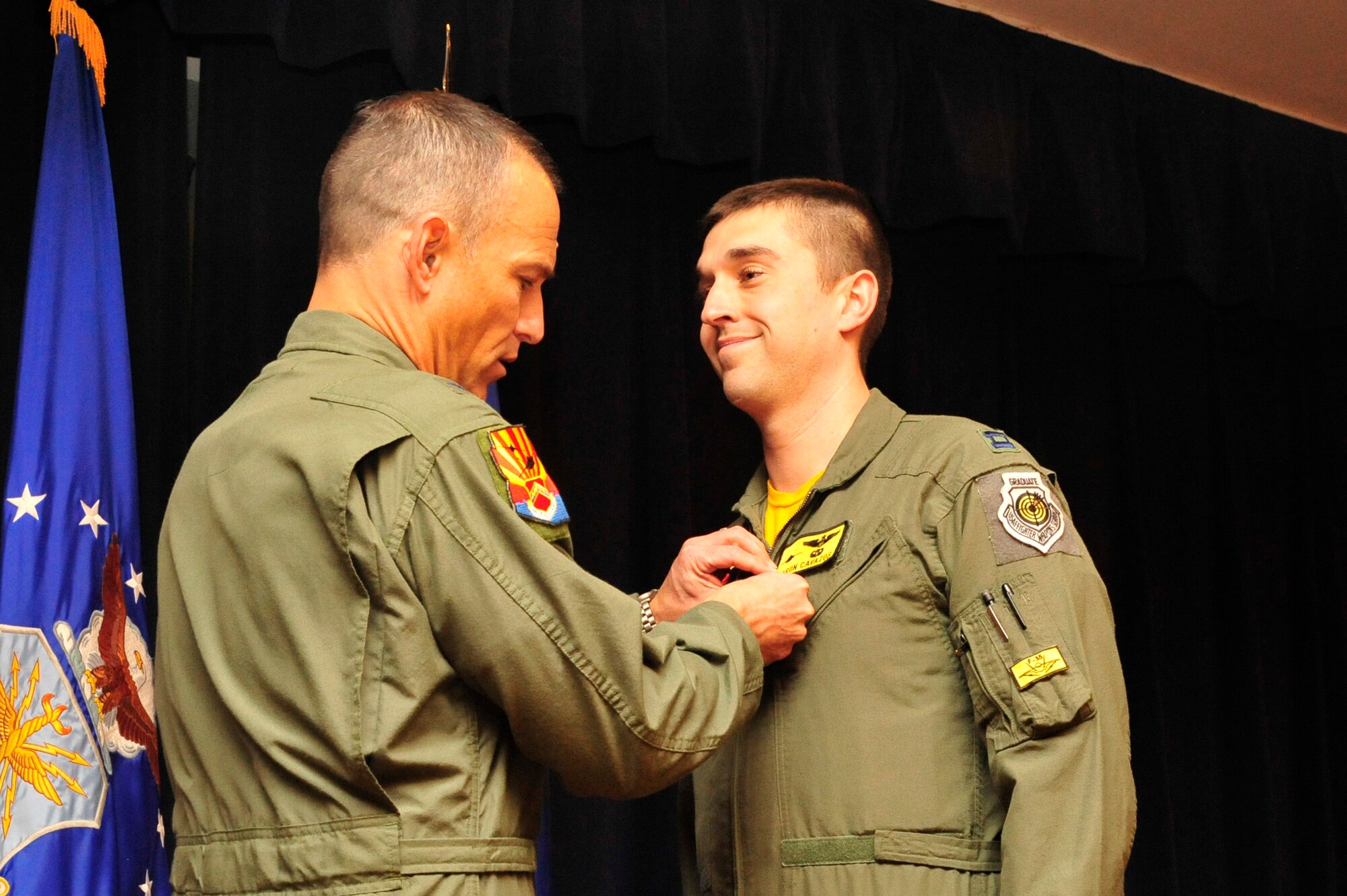 Brig. Gen. Scott Pleus, 56th Fighter Wing commander, pins the Air Force Combat Action Medal onto Capt. Aaron Cavazos, 61st Fighter Squadron weapons officer, Jan. 16 in Club Five Six at Luke Air Force Base. Cavazos was awarded the Air Force Combat Action Medal and the Distinguished Flying Cross with Valor for his heroism while serving in Operation Enduring Freedom Oct. 28, 2008. Cavazos efforts saved the lives of six Marines that day. (U.S. Air Force photo/Senior Airman Grace Lee)