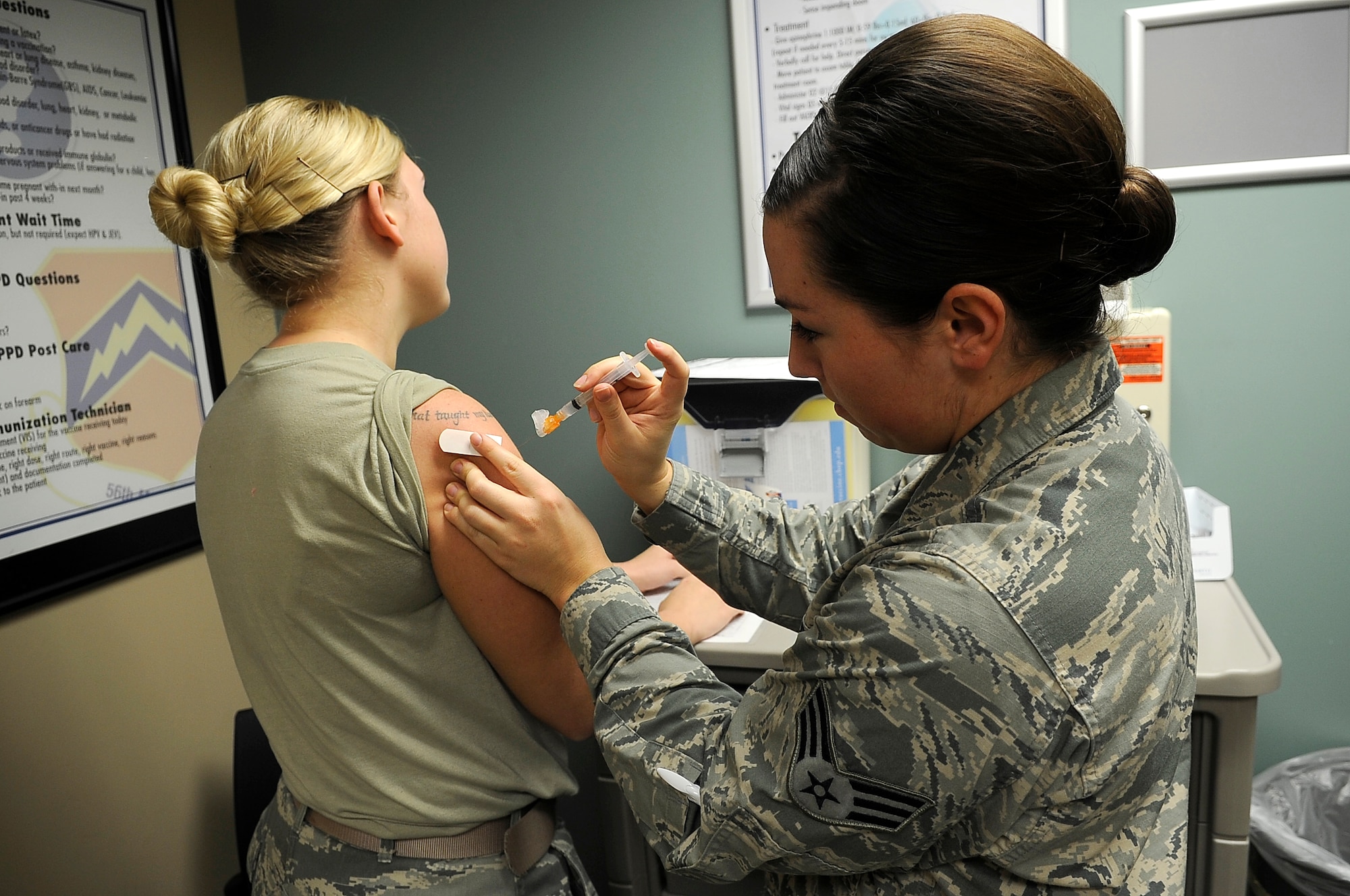 Staff Sgt. Miranda Pyles, 56th Medical Operations Squadron allergy and immunization technician, receives a third dose of the papilloma vaccine Jan. 14 from Senior Airman Cassandra Saunders, 56th MDOS allergy and immunization technician, at Luke Air Force Base. The allergy and immunization clinic also administers allergy tests. (U.S. Air Force photo/Airman Pedro Mota)