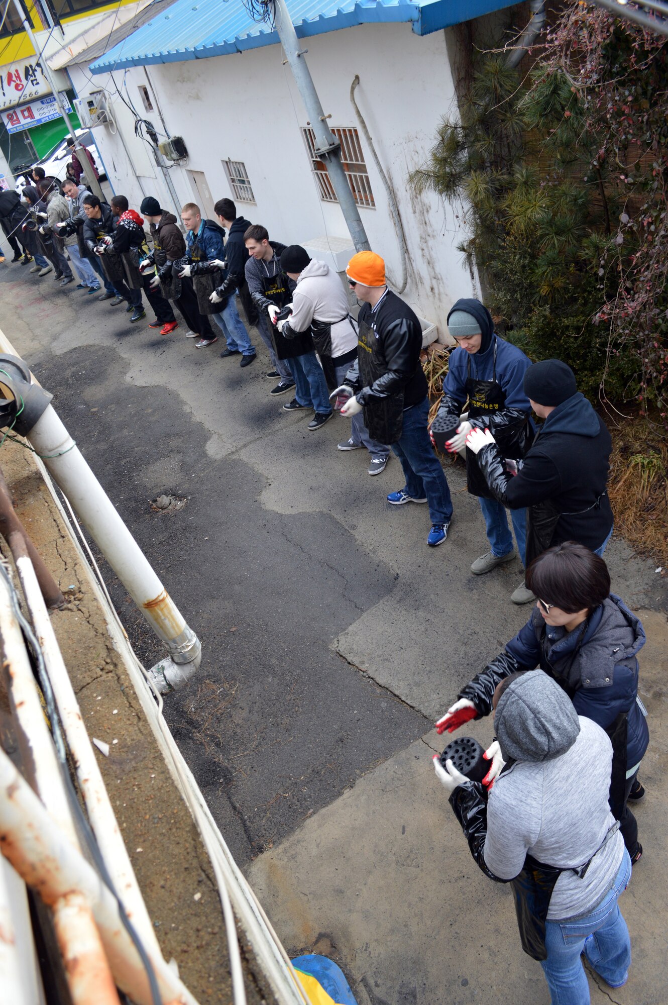 Volunteers from Osan Air Base, Republic of Korea, form a line to unload and deliver coal Jan. 22, 2015 in Songtan, ROK.  Members of Seventh Air Force A2S raised over 2M Won which was used to buy 5,000 coal briquettes, locally called “yeontan.”  The yeonton is being delivered to 27 homes in need.  Each home will be provided with enough to last about three months.  (U.S. Air Force photo by Master Sgt. Marelise Wood)