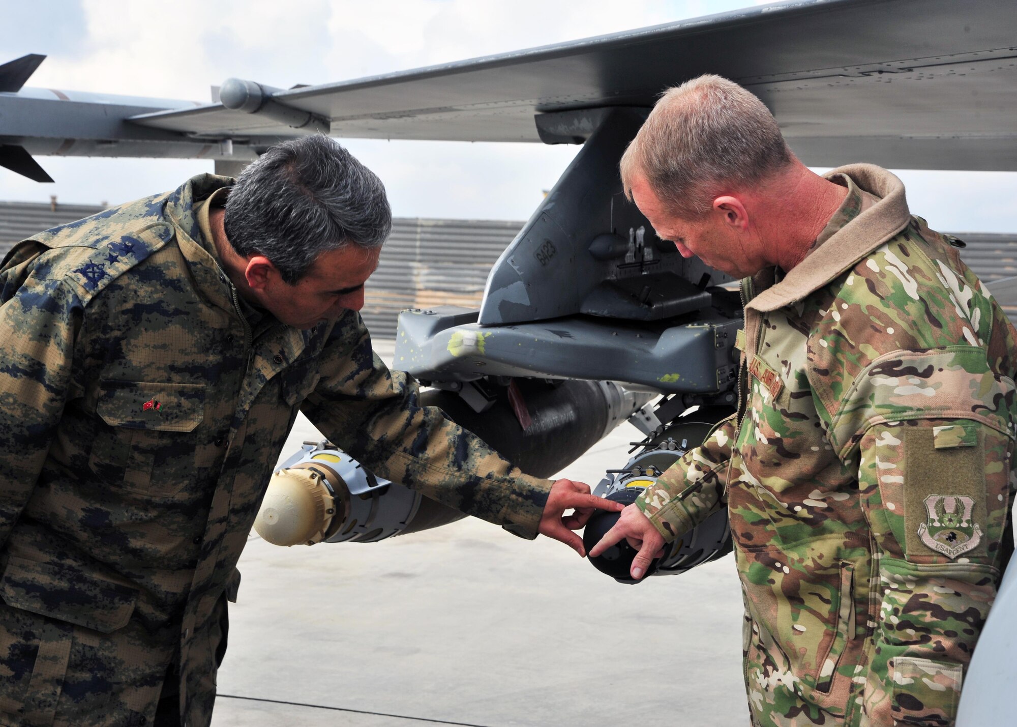 U.S. Air Force Brig. Gen. Mark Kelly, 455th Air Expeditionary Wing commander, and Air Force Maj. Gen.  Mehmet Cahit Bakir, Commander of Kabul International Airport, examine munitions on an F-16 Fighting Falcon during a tour Jan. 22, 2015 at Bagram Airfield, Afghanistan. During the tour, Bakir had the opportunity to meet with 455th Air Expeditionary Wing leadership and become better acquainted with Air Force assets and squadrons here. (U.S. Air Force photo by Staff Sgt. Whitney Amstutz/released)