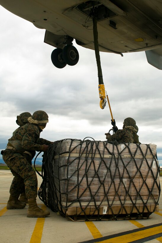 U.S. Marine landing support specialists with Special-Purpose Marine Air-Ground Task Force Crisis Response-Africa attach a pallet of supplies to an MV-22 Osprey during an external lift drill at Morón Air Base, Spain, Jan. 19, 2015. The Marines used a grounding cable to counter the static-electric charge generated by the Osprey before attaching a 2180-pound pallet to complete the lift. (U.S. Marine Corps photo by Sgt. Paul Peterson)