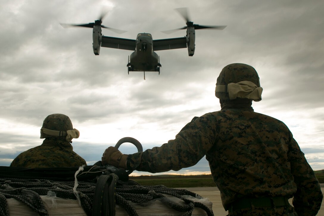 U.S. Marine landing support specialists with Special-Purpose Marine Air-Ground Task Force Crisis Response-Africa brace for the arrival of an MV-22 Osprey at Morón Air Base, Spain, Jan. 19, 2015. The Osprey produced hurricane-like winds that buffeted the Marines on the ground as they attached a 2,180-pound pallet of supplies to a lift cable underneath the aircraft. (U.S. Marine Corps photo by Sgt. Paul Peterson)