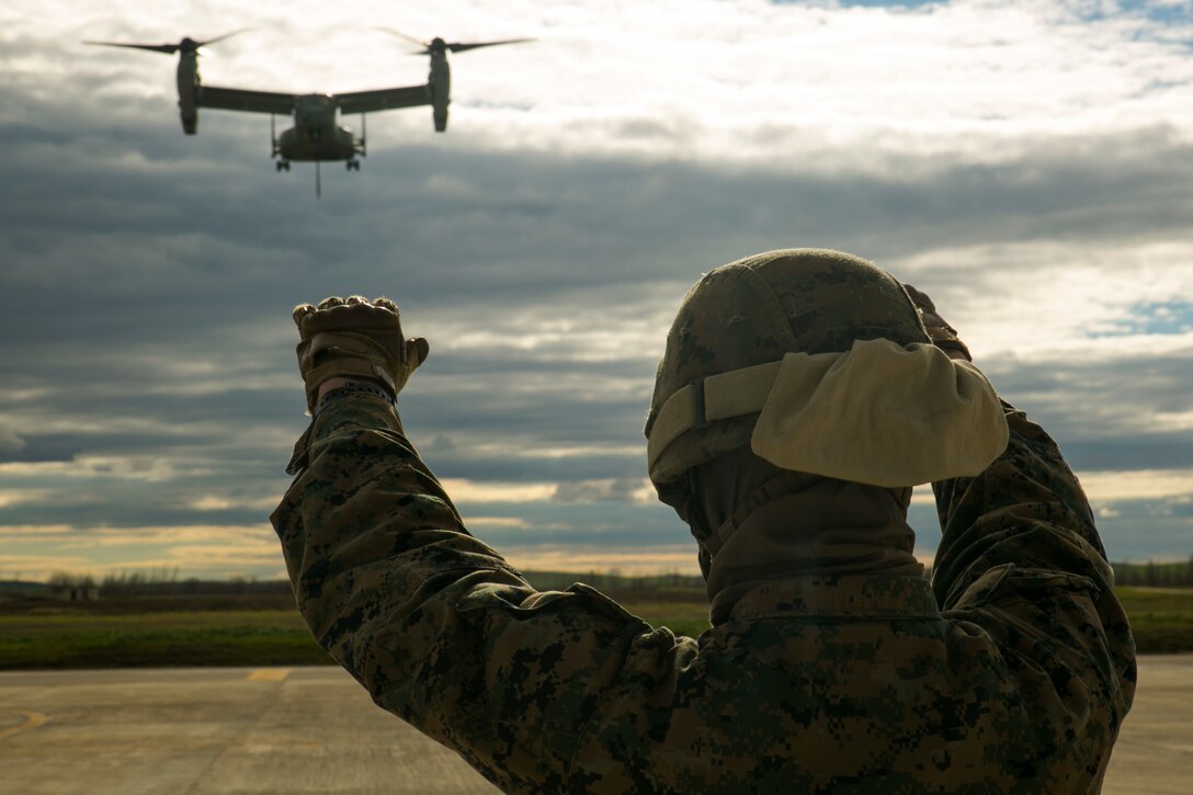 A U.S. Marine landing support specialist with Special-Purpose Marine Air-Ground Task Force Crisis Response-Africa guides an MV-22 Osprey during an external-lift drill at Morón Air Base, Spain, Jan. 19, 2015. Hand signals from Marines on the ground allowed the pilots maneuver over cargo that not visible from their vantage point in the air. (U.S. Marine Corps photo by Sgt. Paul Peterson)