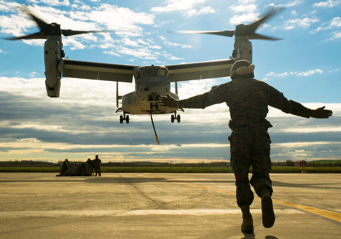 U.S. Marine Lance Cpl. Cody Keller, a landing support specialist with Special-Purpose Marine Air-Ground Task Force Crisis Response-Africa, signals an MV-22 Osprey during an external-lift drill at Morón Air Base, Spain, Jan. 19, 2015. Keller had to brace against hurricane-like winds from the Osprey’s rotors to provide signals to the pilots as they maneuvered over a 2180-point pallet. (U.S. Marine Corps photo by Sgt. Paul Peterson)