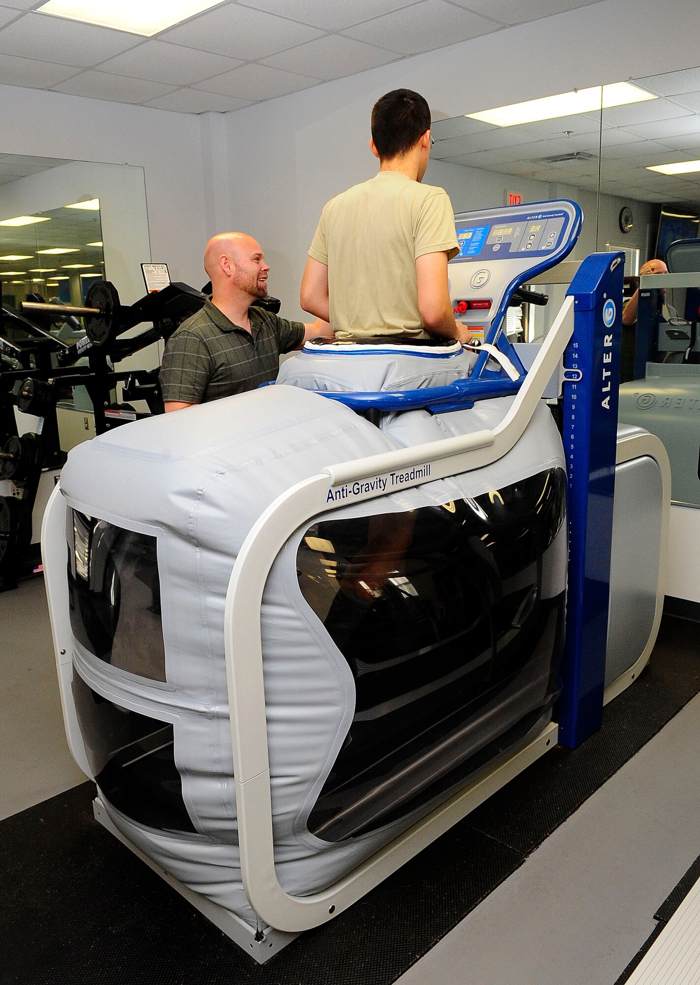 Eddie Capps, 1st Special Operations Medical Operations Squadron physical therapist assistant, assists Airman 1st Class Timothy Montano, 1st Special Operations Medical Operations Squadron physical therapist technician, on the Anti-Gravity Treadmill on Hurlburt Field, Fla., Jan. 14, 2015.  The treadmill is used to increase the training load for exercise-induced injuries; this helps Airmen work back into proper running form. (U.S. Air Force photo/Airman 1st Class Andrea Posey)