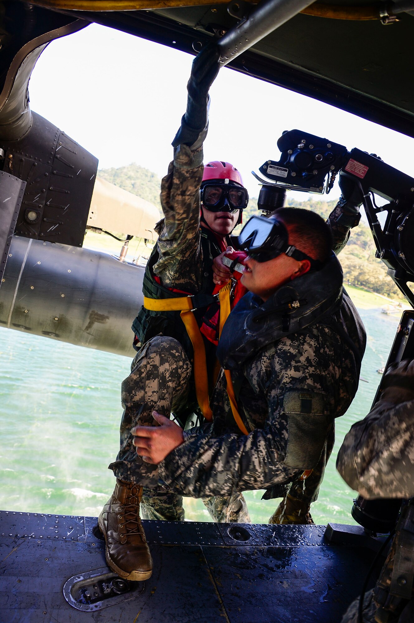 A medic from the 1-228th Aviation Battalion climbs in to a UH-60 Black Hawk helicopter after being lowered to retrieve a the U.S. Army Special Operations member from Lake Yojoa, Honduras, Jan. 22, 2015.   The 1-228th Aviation Regiment partnered with U.S. Army Special Operations personnel to practice recovering live personnel. The over-water hoist training was held to ensure members of Joint Task Force-Bravo are planning and preparing for crisis and contingency response, as well as countering transnational organized crime, and counterterrorism operations as part of U.S. Southern Command’s mission. Contingency planning prepares the command for various scenarios that pose the greatest probability of challenging our regional partners or threatening our national interests. (U.S. Air Force photo/Tech. Sgt. Heather Redman)