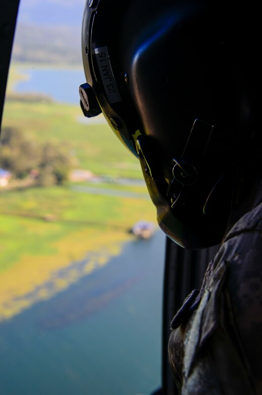 A crew chief assigned to the 1-228th Aviation Regiment looks for the U.S. Army Special Operations members in Lake Yojoa, Honduras, Jan. 22, 2015.   The 1-228th Aviation Regiment partnered with U.S. Army Special Operations personnel to practice recovering live personnel. The over-water hoist training was held to ensure members of Joint Task Force-Bravo are planning and preparing for crisis and contingency response, as well as countering transnational organized crime, and counterterrorism operations as part of U.S. Southern Command’s mission. Contingency planning prepares the command for various scenarios that pose the greatest probability of challenging our regional partners or threatening our national interests. (U.S. Air Force photo/Tech. Sgt. Heather Redman)