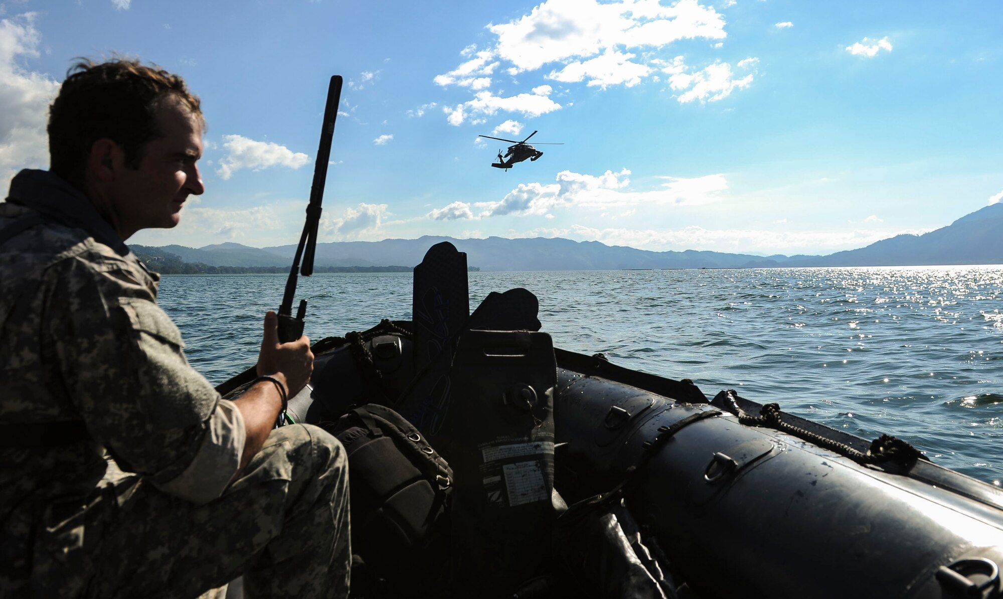 A member of U.S. Army Special Operations Forces communicates with the pilots of a UH-60 Black Hawk helicopter assigned to the 1-228th Aviation Battalion during hoist training at Lake Yojoa, Honduras, Jan. 22, 2015. The 1-228th Aviation Regiment partnered with U.S. Army Special Operations personnel to practice recovering live personnel. The overwater hoist training was held to ensure members of Joint Task Force-Bravo are planning and preparing for crisis and contingency response, as well as countering transnational organized crime, and counterterrorism operations as part of U.S. Southern Command’s mission. Contingency planning prepares the command for various scenarios that pose the greatest probability of challenging our regional partners or threatening our national interests. (U.S. Air Force photo/Tech. Sgt. Keola Soon)
