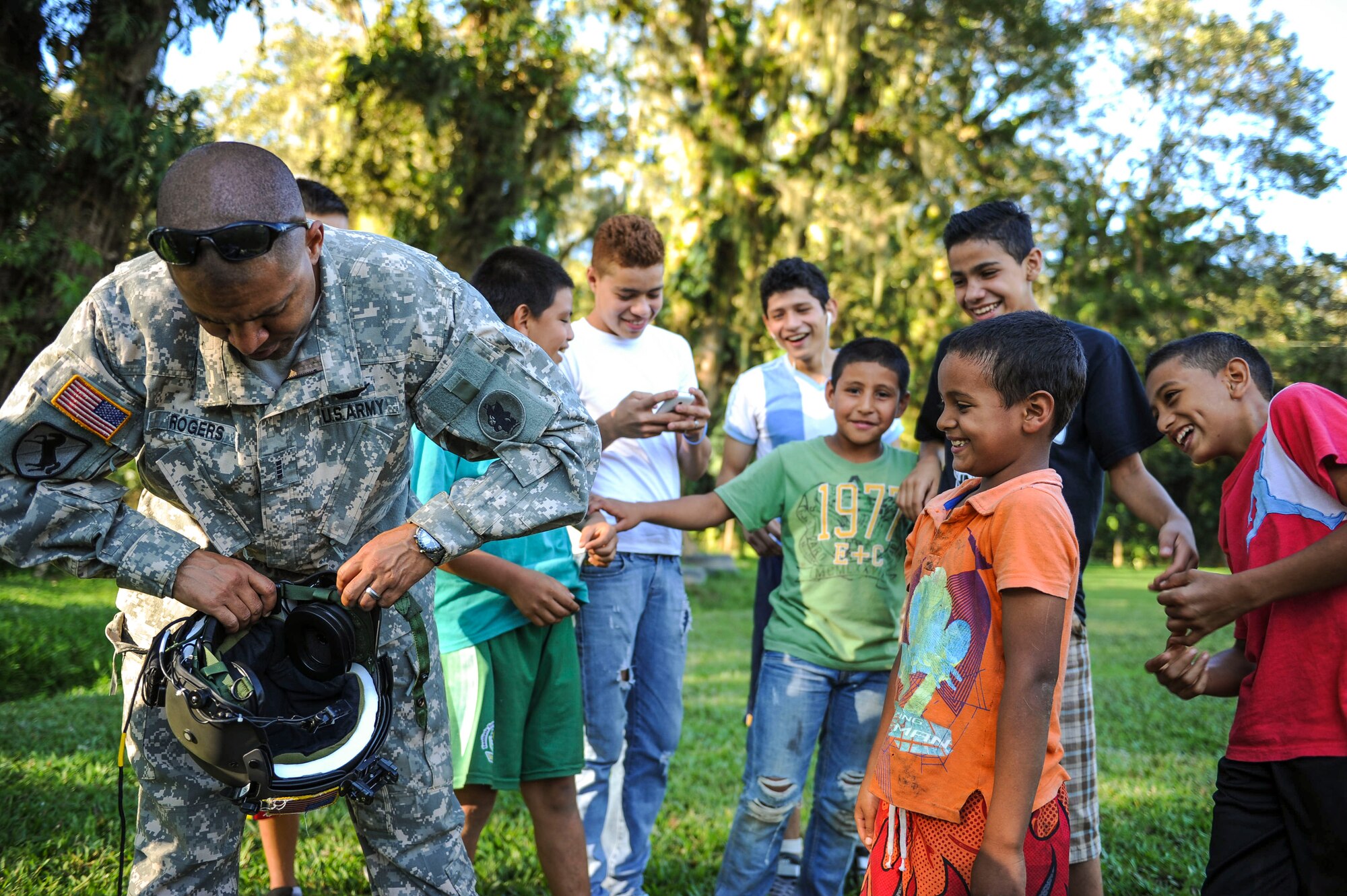 U.S. Army Chief Warrant Officer 4 Ronald Rodgers, 1-228th Aviation Regiment battalion safety officer, adjusts his helmet for a young boy to try at Lake Yojoa, Honduras, Jan. 22, 2015.   The 1-228th Avn. Reg. partnered with U.S. Army Special Operations personnel to practice recovering live personnel. The over-water hoist training was held to ensure members of Joint Task Force-Bravo are planning and preparing for crisis and contingency response, as well as countering transnational organized crime, and counterterrorism operations as part of U.S. Southern Command’s mission. Contingency planning prepares the command for various scenarios that pose the greatest probability of challenging our regional partners or threatening our national interests. (U.S. Air Force photo/Tech. Sgt. Keola Soon)