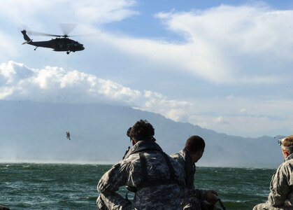 U.S. Army Special Operations members monitor their team-mates as members of the 1-228th Aviation Regiment hoist them out of Lake Yojoa, Honduras, Jan. 22, 2015.   The 1-228th Avn. Reg. partnered with U.S. Army Special Operations personnel to practice recovering live personnel. The over-water hoist training was held to ensure members of Joint Task Force-Bravo are planning and preparing for crisis and contingency response, as well as countering transnational organized crime, and counterterrorism operations as part of U.S. Southern Command’s mission. Contingency planning prepares the command for various scenarios that pose the greatest probability of challenging our regional partners or threatening our national interests. (U.S. Air Force photo/Tech. Sgt. Keola Soon)