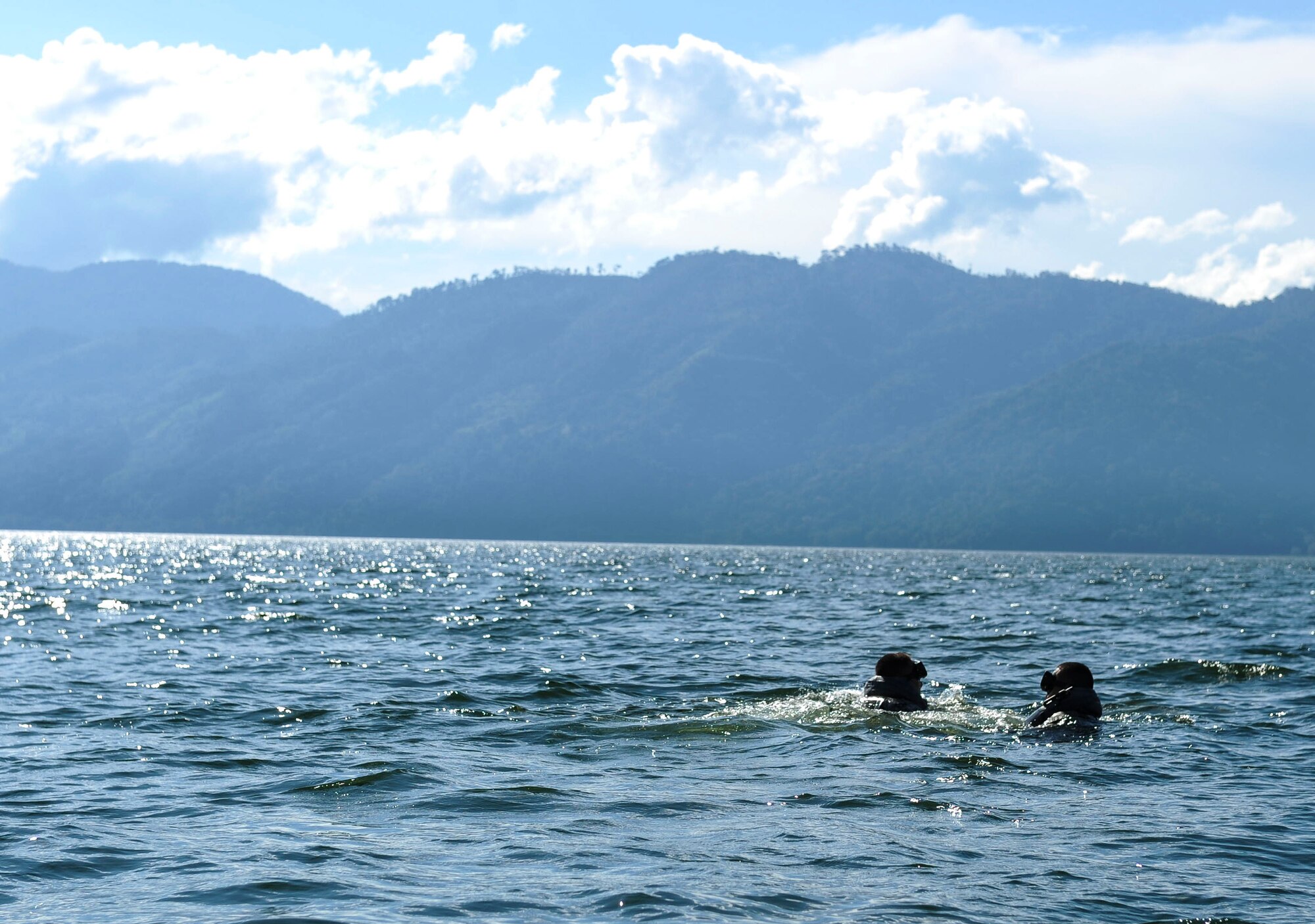Two U.S. Army Special Operations members swim out to the middle of Lake Yojoa to wait for a UH-60 Black Hawk helicopter assigned to the 1-228th Aviation Regiment to recover them during an over-water hoist training event in Honduras, Jan. 22, 2015.   The 1-228th Avn. Reg. partnered with U.S. Army Special Operations personnel to practice recovering live personnel. The overwater hoist training was held to ensure members of Joint Task Force-Bravo are planning and preparing for crisis and contingency response, as well as countering transnational organized crime, and counterterrorism operations as part of U.S. Southern Command’s mission. Contingency planning prepares the command for various scenarios that pose the greatest probability of challenging our regional partners or threatening our national interests. (U.S. Air Force photo/Tech. Sgt. Keola Soon)