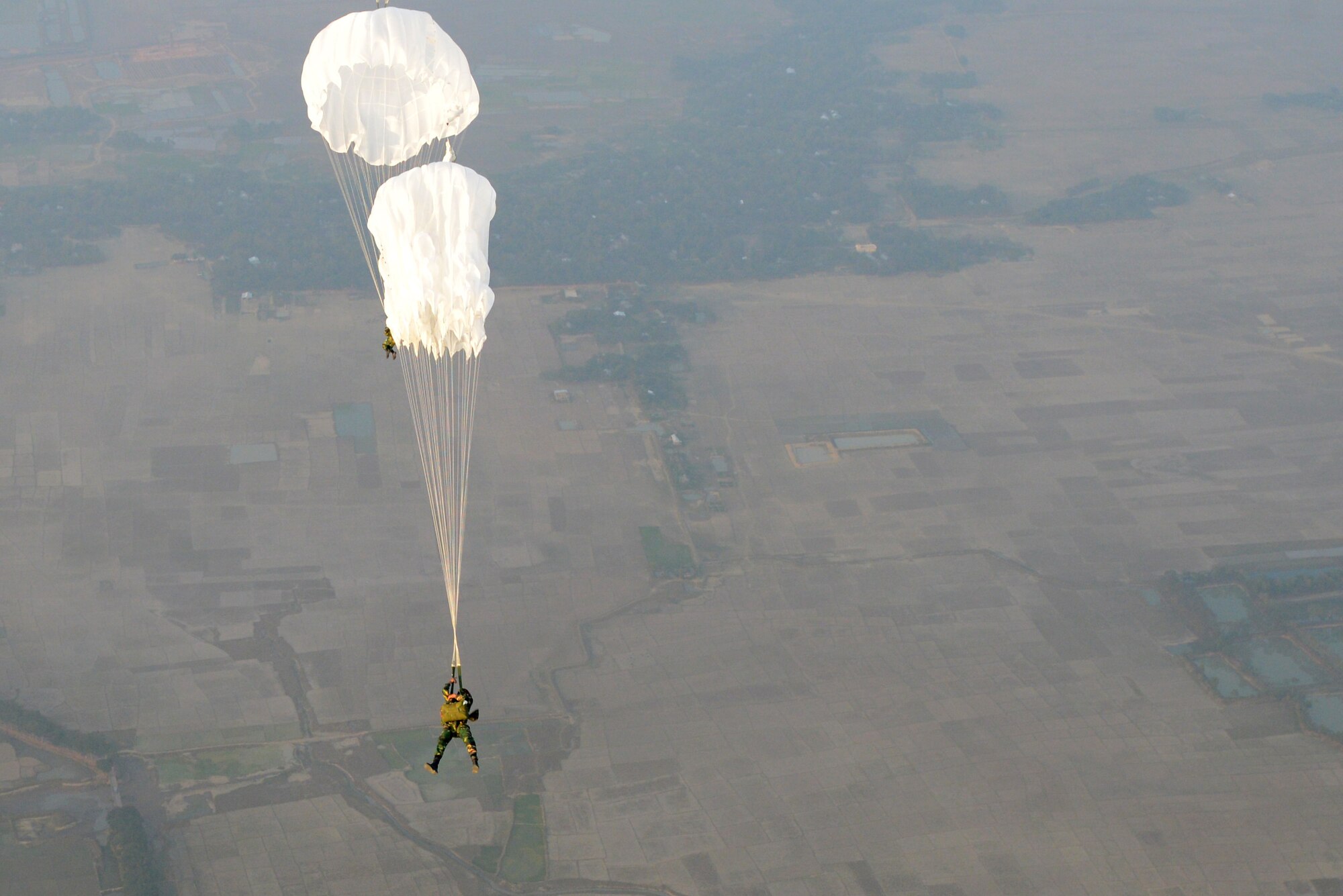 Bangladeshi commandos jump from a U.S. Air Force C-130H aircraft over a drop zone during Exercise COPE SOUTH near Sylhet, Bangladesh, Jan. 24, 2015. COPE SOUTH helps cultivate common bonds, foster goodwill, and improve readiness and compatibility between members of the Bangladesh and U.S. Air Forces. (U.S. Air Force photo by 1st Lt. Jake Bailey/Released)