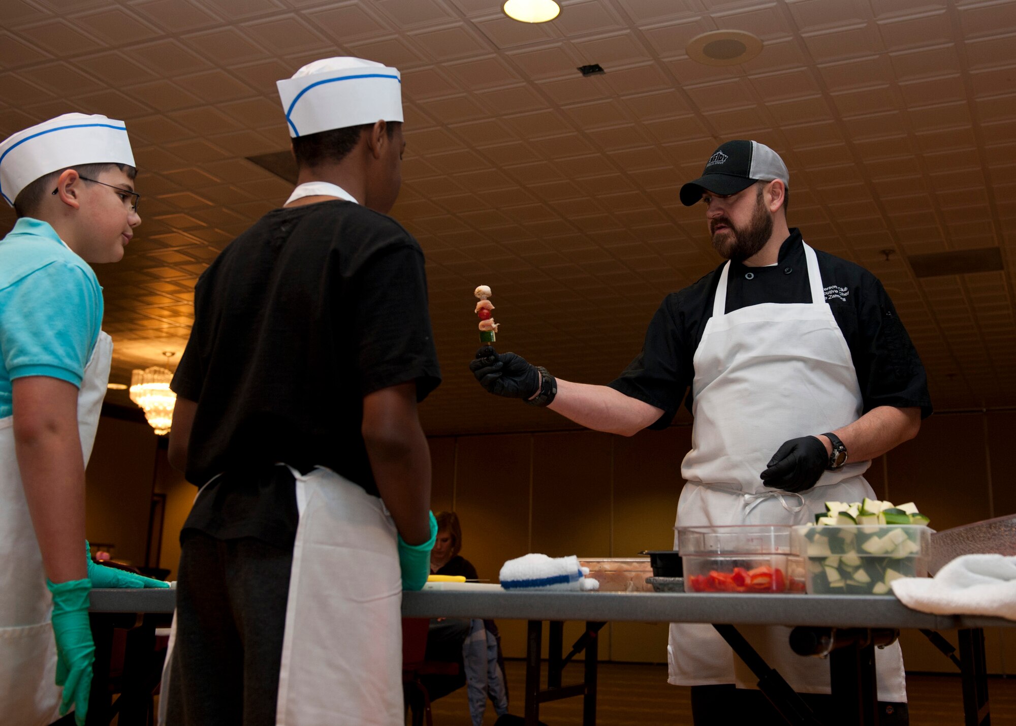 PETERSON AIR FORCE BASE, Colo. –Joe Zamora, The Club executive chef, teaches kids how to assemble a chicken kabob during the Kids Barbeque Cooking Camp at The Club, Jan. 17, 2015. The kids learned barbecue and grill techniques along with how to prepare a full meal including chicken kabobs, tilapia, homemade barbecue sauce, salad and a desert. (U.S. Air Force photo by Senior Airman Tiffany DeNault)