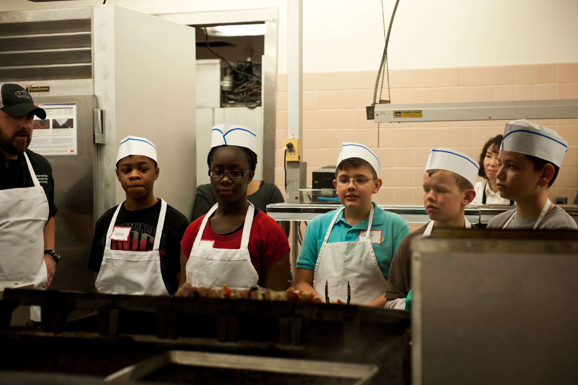 PETERSON AIR FORCE BASE, Colo. – Kids participating in the Kids Barbeque Cooking Camp patiently wait for chicken kabobs to cook at The Club, Jan. 17, 2015. Taught by chefs Joe Zamora and Kirk Dunning, the kids learned barbecue and grill techniques along with how to prepare a full meal including chicken kabobs, tilapia, homemade barbecue sauce, salad and a desert. (U.S. Air Force photo by Senior Airman Tiffany DeNault)